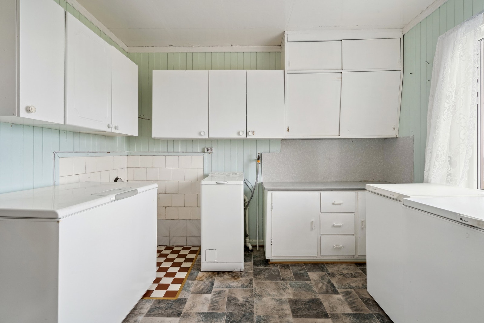 Opplegg for vaskemaskin i 1. etasjer med eldre kjøkkeninnredning og plass til fryser. Galleribilde