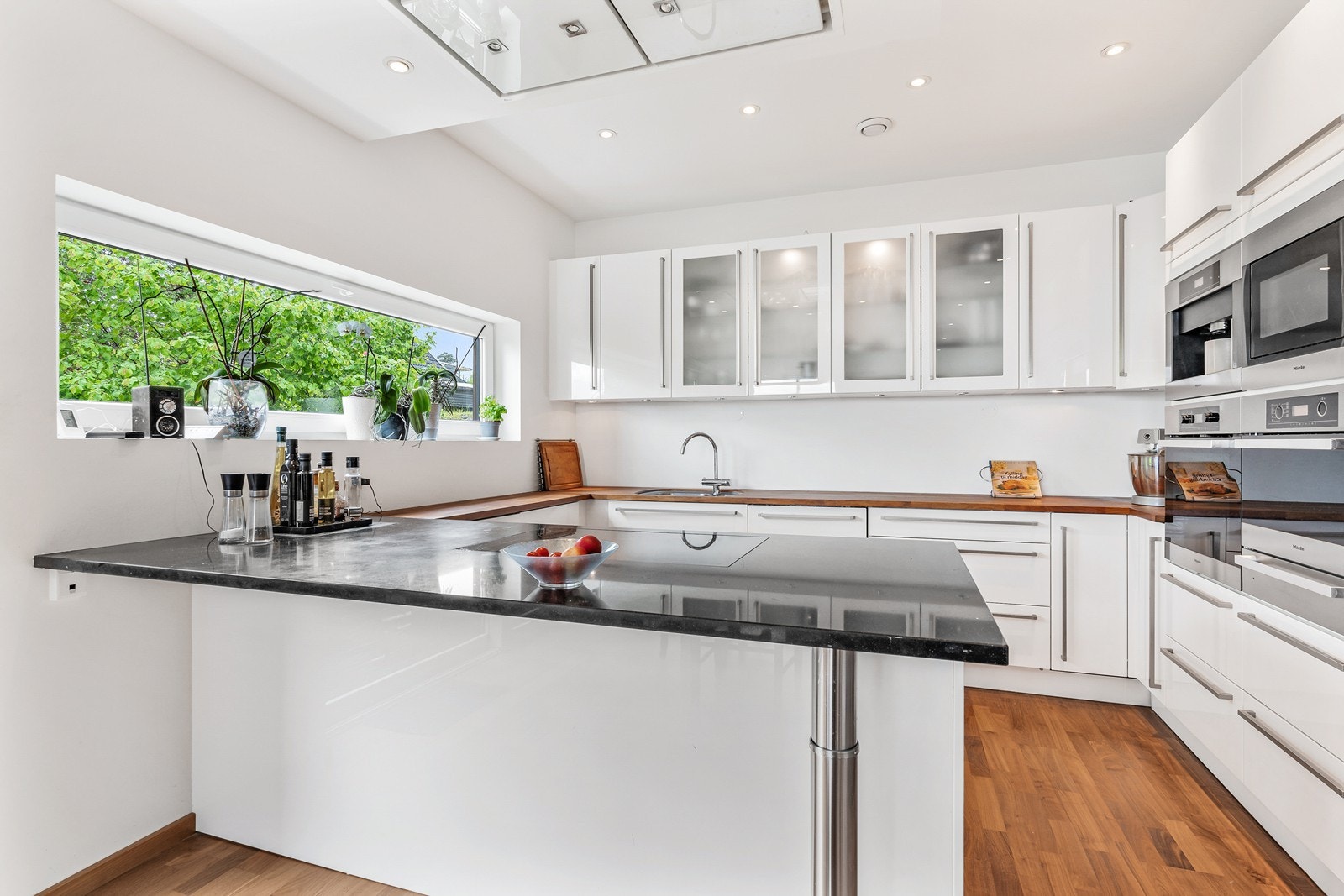 Kjøkken fra Schmidt med glatte hvite fronter og benkeplate i stein og tre. Galleribilde