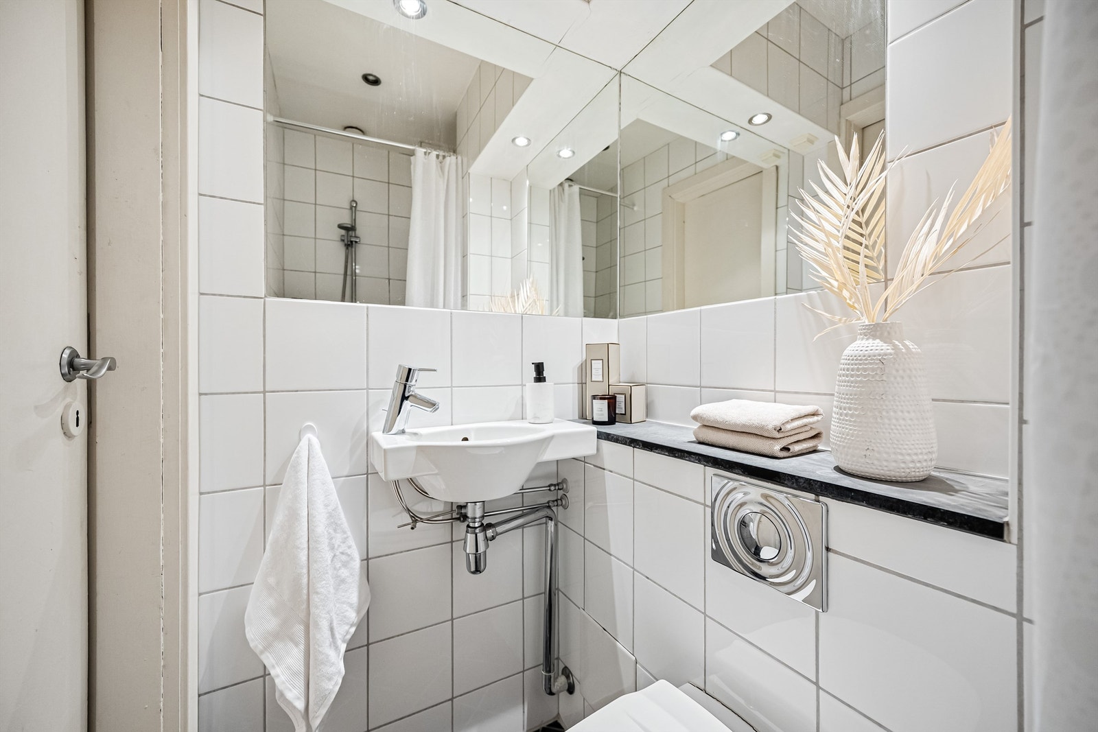 Badet har vegghengt servant med ett-greps armatur og innmurt speil, overlys og stikkontakt på vegg over servant. Galleribilde
