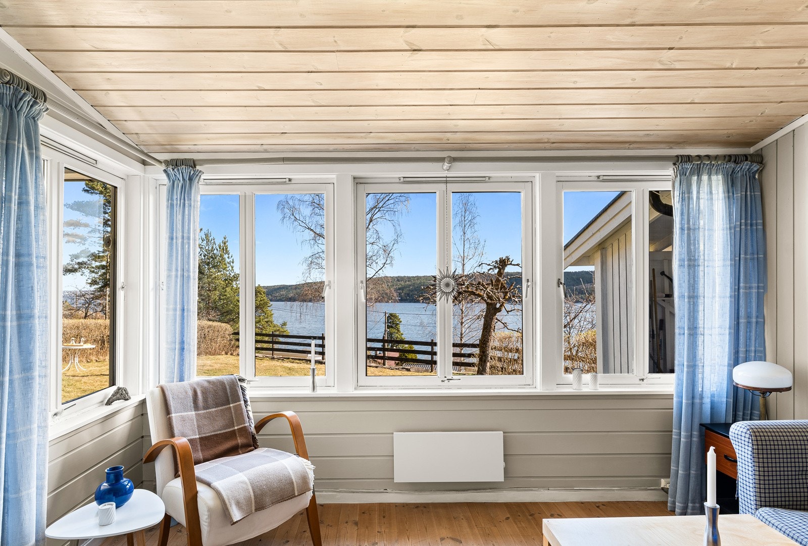 Vindusrekken strekker seg langs hele veggen og åpner rommet mot naturen utenfor. Galleribilde