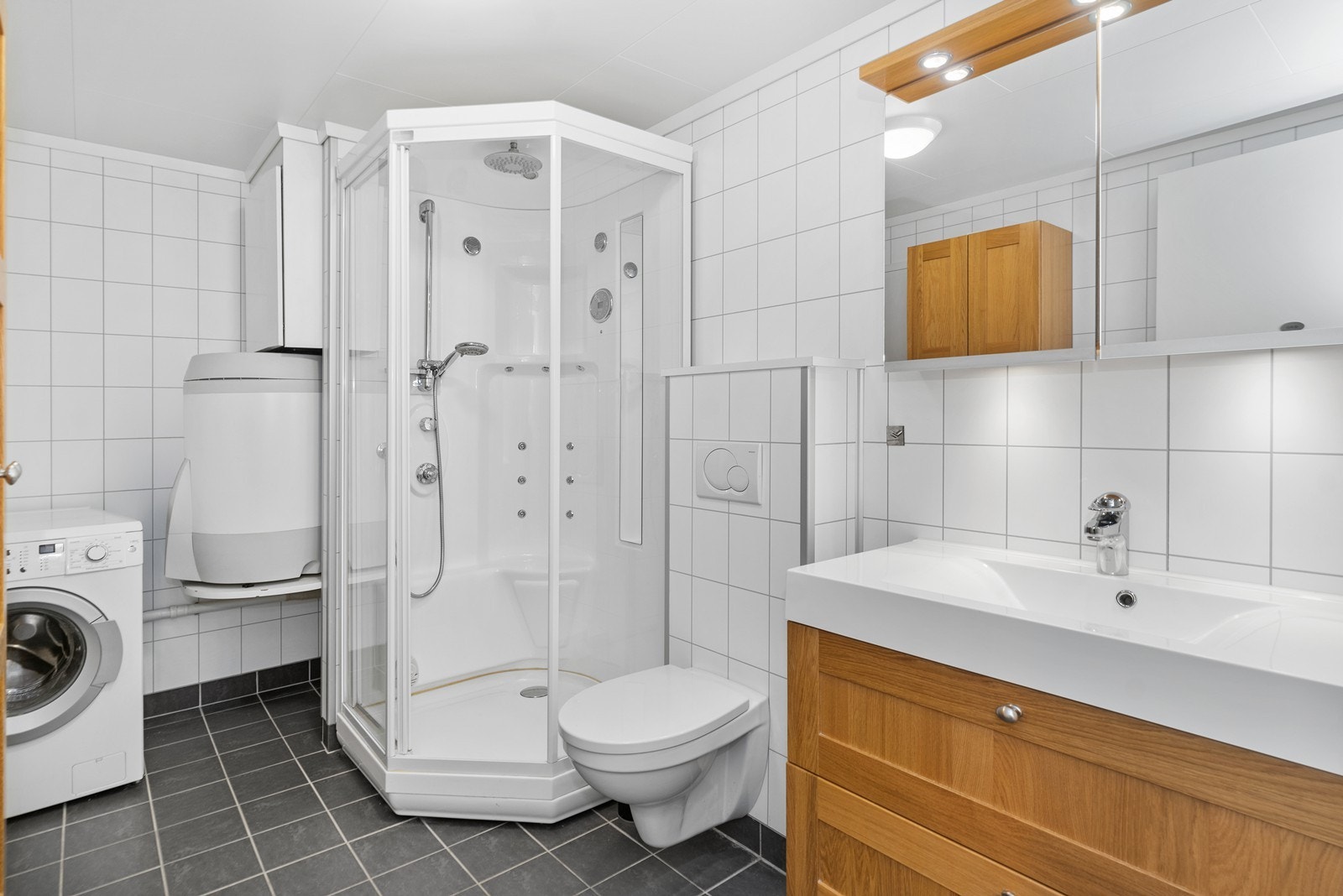 Badet er innredet med servant med underskap, vegghengt toalett og dusjkabinett. Galleribilde