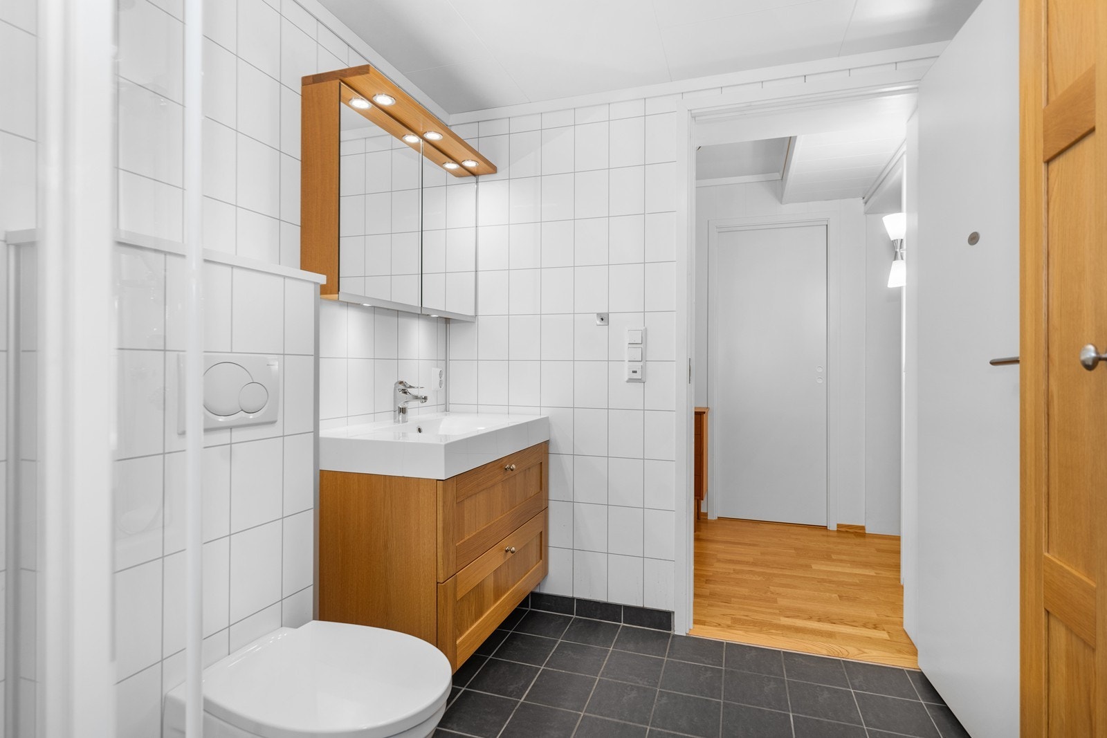 Badet har flislagt gulv, våtromsplater på veggene og malt himling. Galleribilde
