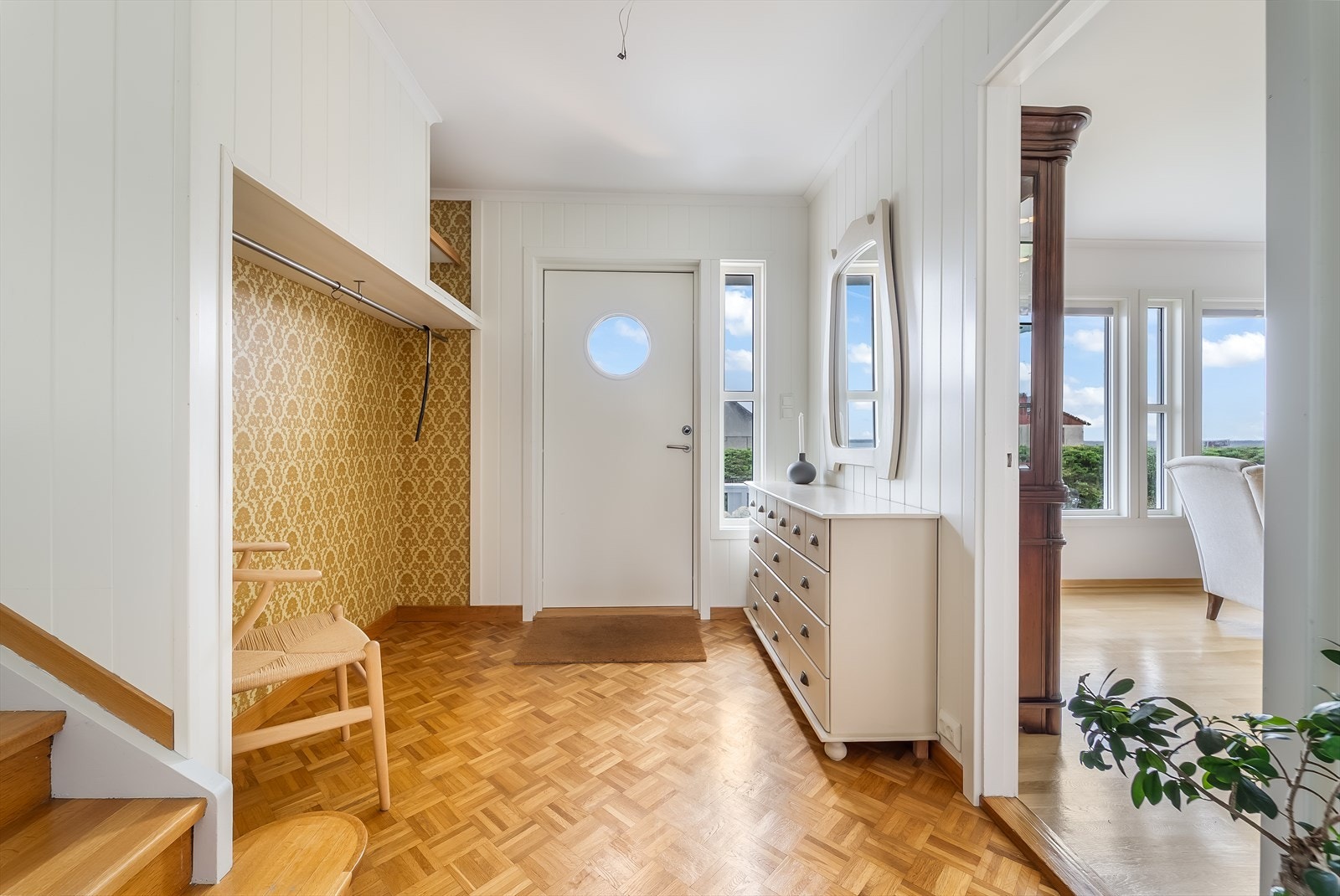 Innbydende gang med avkledningsplass. Innslag av originalt gulv og tapet på vegg. Galleribilde