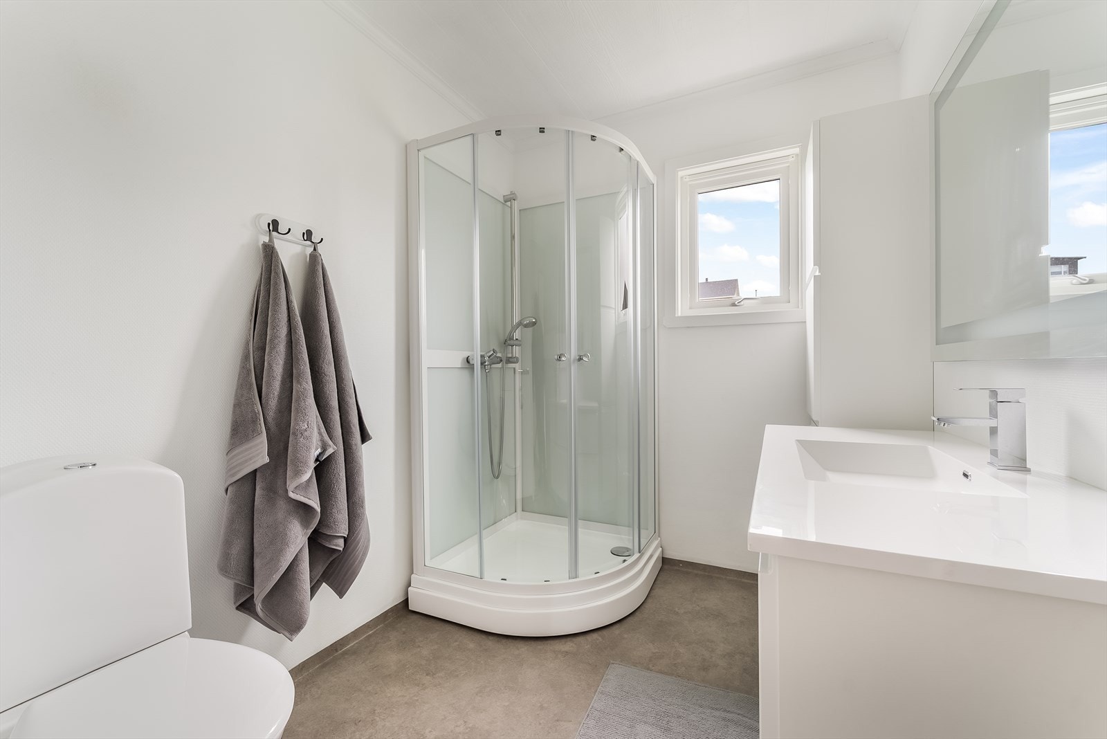 Pent bad med belegg på gulv og malte flater på vegg. Innredet med baderomsinnredning, toalett og dusjkabinett. Galleribilde