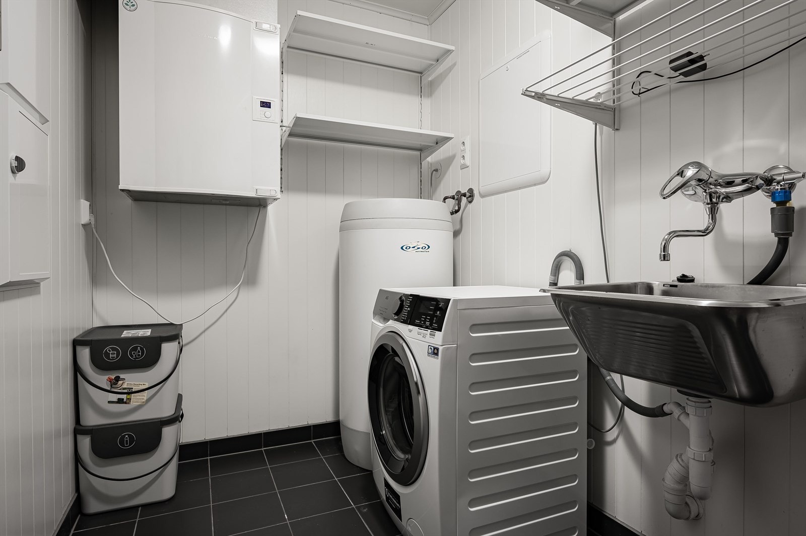 Leiligheten har også en innvendig bod/teknisk rom med utslagskum og opplegg for vaskemaskin. Rommet har mørke fliser på gulv med gulvvarme og mekanisk avtrekk. Galleribilde
