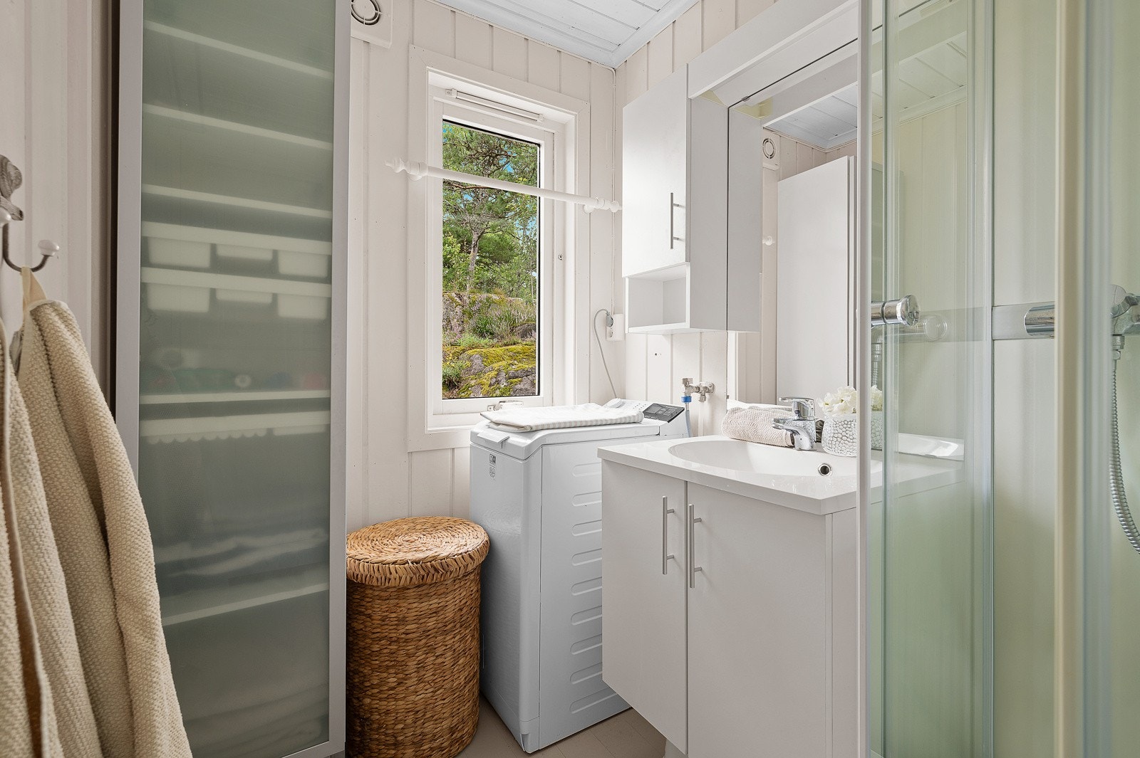 Hyttas bad har dusjkabinett, servant med innredning og opplegg til vaskemaskin. Galleribilde