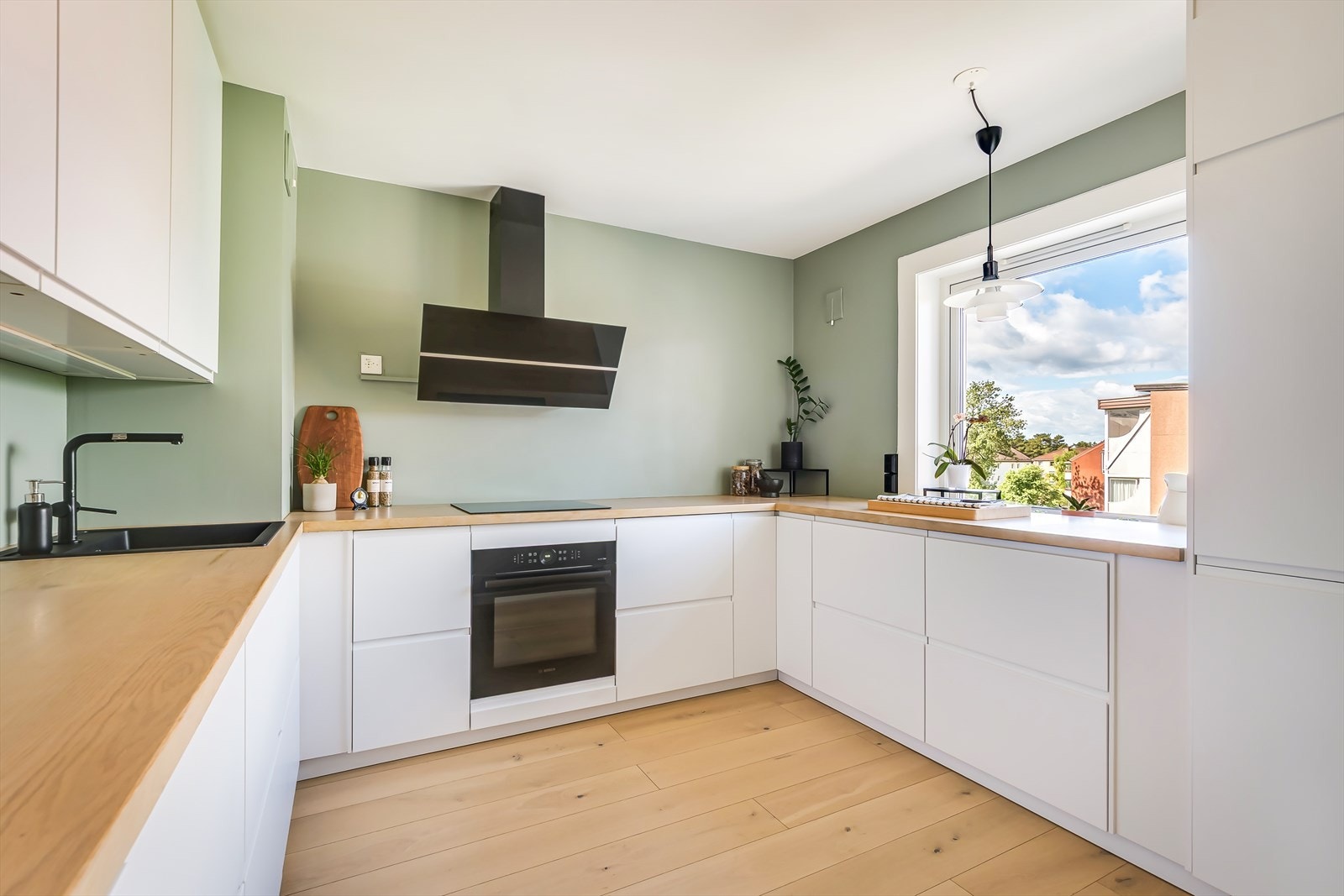 Kjøkkenet er både funksjonelt og stilfullt med hvite, slette fronter og benkeplate i eik Galleribilde