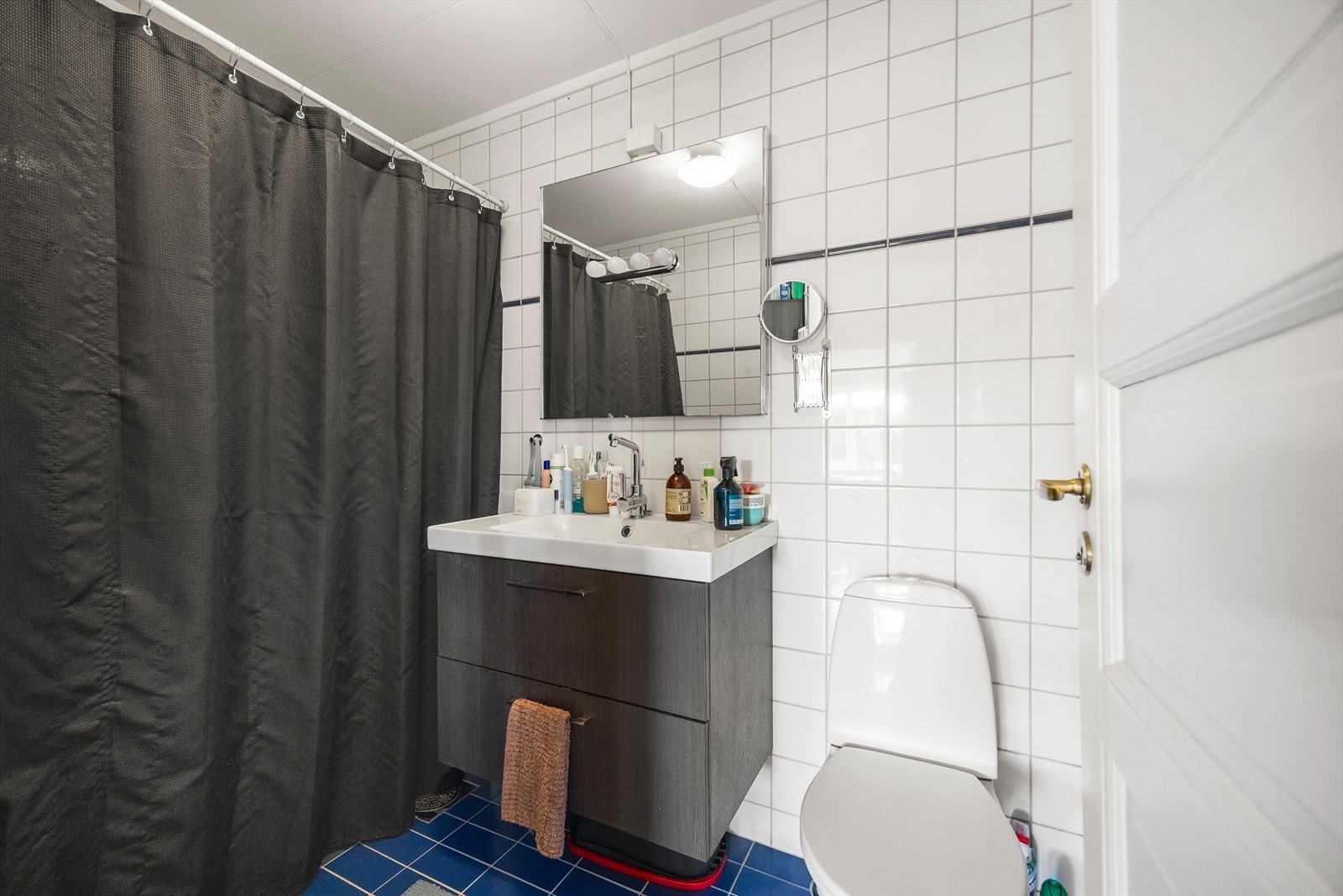 Pent, flislagt baderom med elektrisk gulvvarme. Badet er innredet med klosett, servant og dujshjørne med forheng. Det er opplegg for vaskemaskin og naturlig ventilasjon. Galleribilde