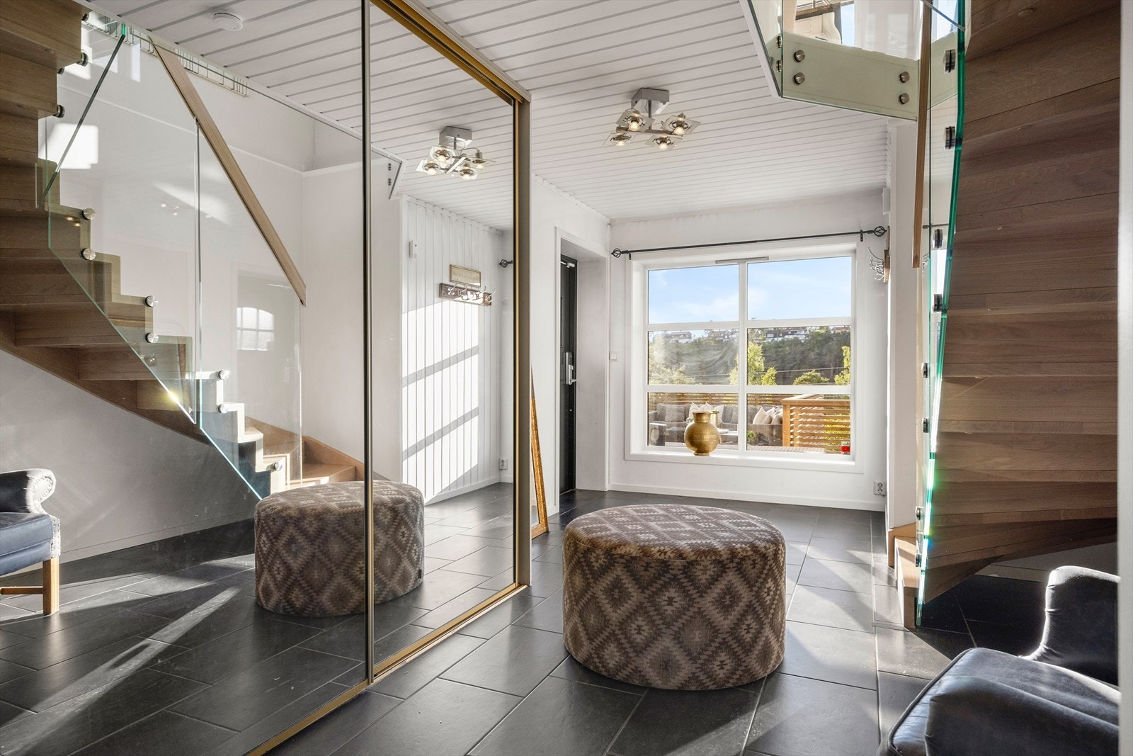 Velkommen inn! Boligen har en innbydende entré med gulvvarme, noe som skaper et umiddelbart godt førsteinntrykk. Det er svært god plass til oppbevaring av yttertøy i den romslige skyvedørsgarderoben med speilfronter. Galleribilde