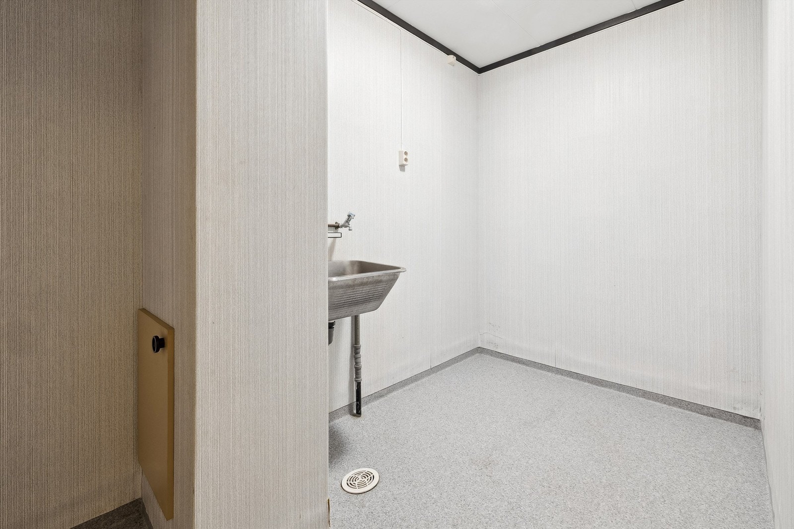 Vaskerom i underetasjen innredet med vegghengt utslagsvask og opplegg for vaskemaskin Galleribilde