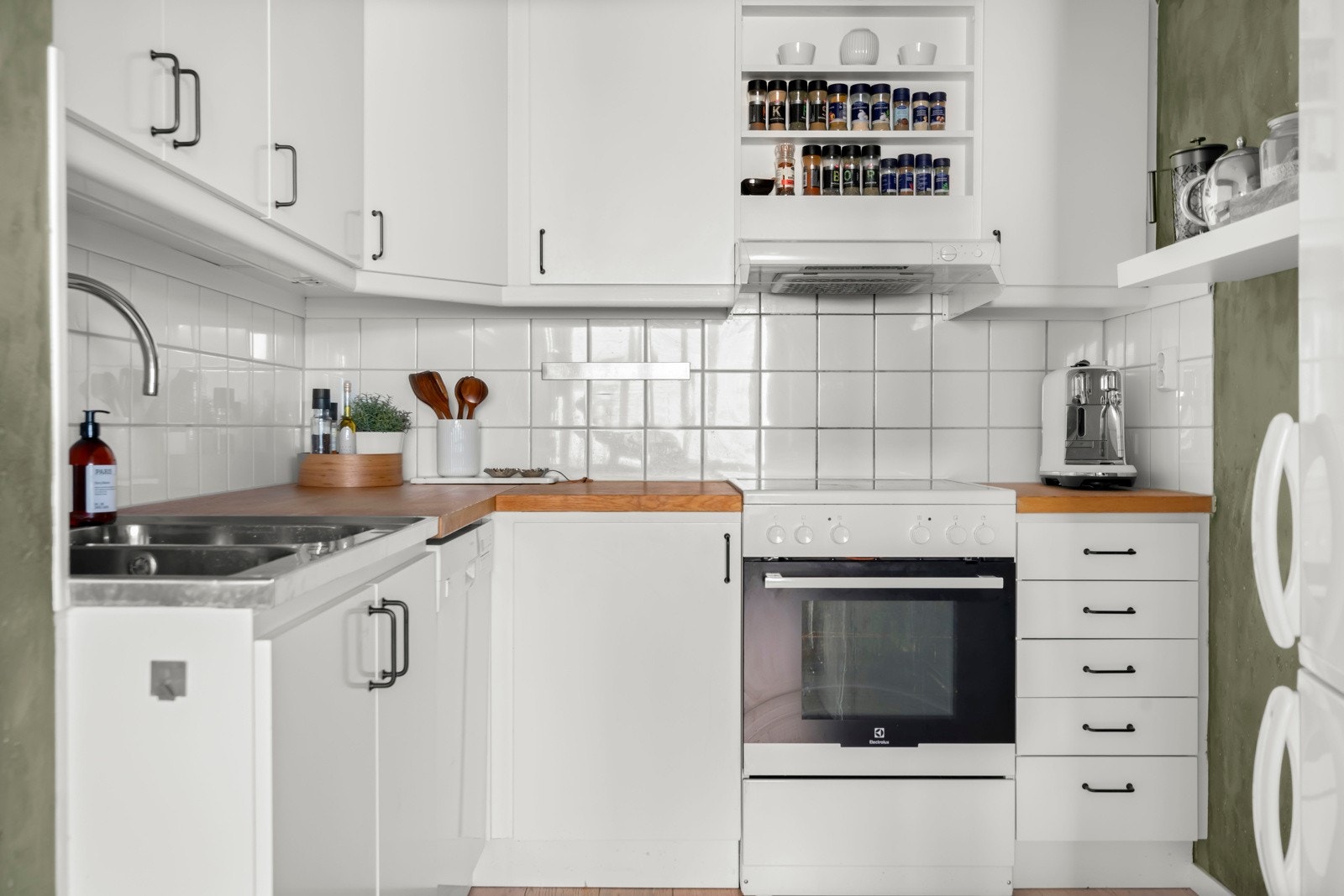 Innredning med glatte, folierte fronter og slitesterk benkeplate i heltre. Kjøkkenet har opplegg for komfyr med topp og oppvaskmaskin. Galleribilde