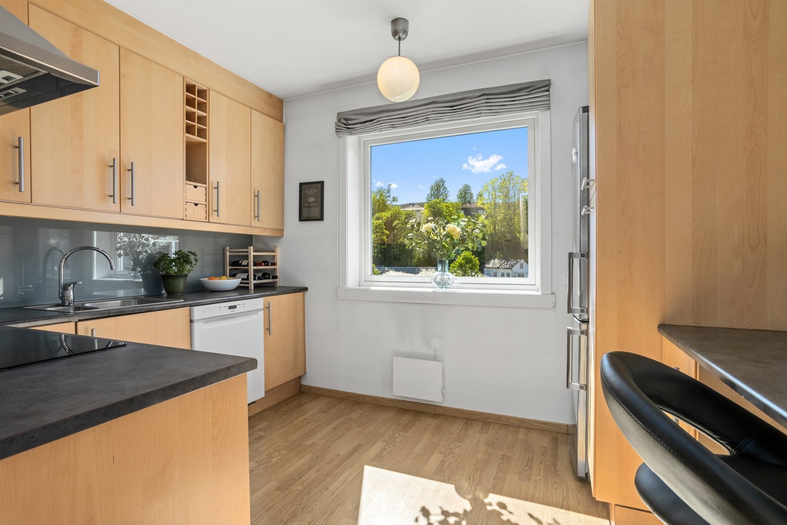 Koselig kjøkkeninnredning med glatte fronter. Benkeplate av laminat med nedfelt oppvaskkum og platetopp Galleribilde