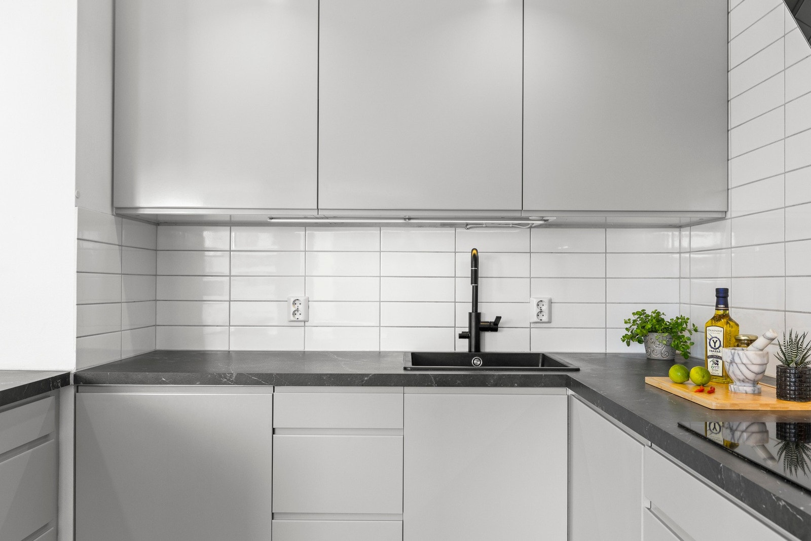 Kjøkkenet har lyse flater med fliser over benkeplaten Galleribilde