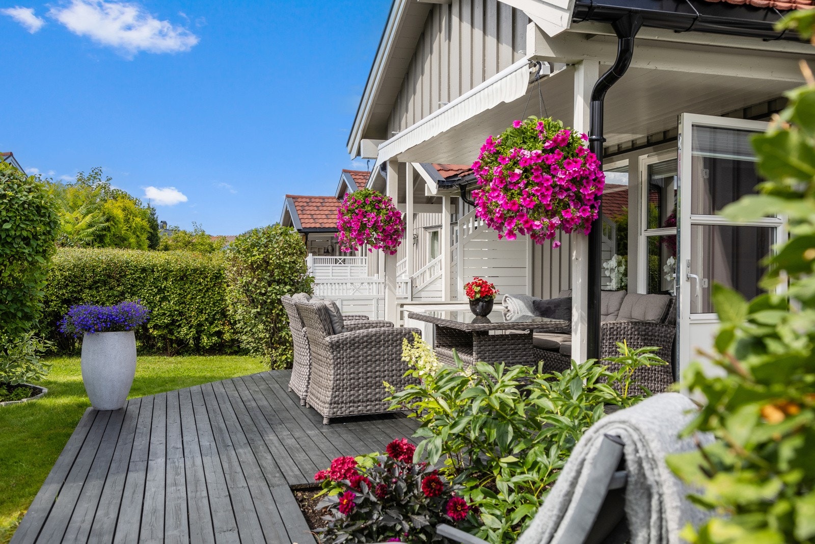 Stor usjenert terrasse og frodig grønn hage som omkranser boligen Galleribilde