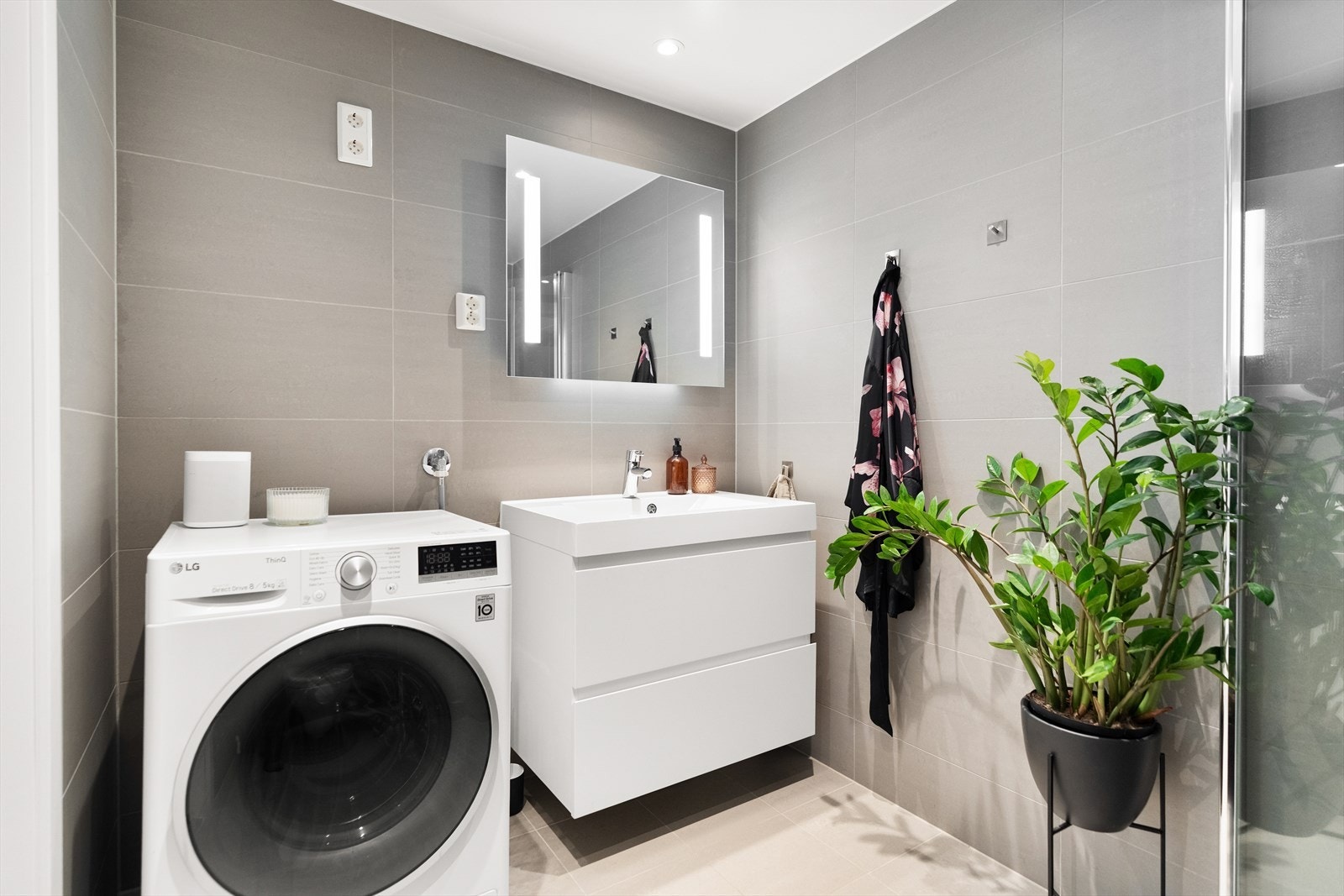 Badet er delikat innredet med tidsriktige fliser, downlights i himling og gulvvarme.Innredningen består av et hvitt vegghengt servantskap med skuffer og speil med belysning Galleribilde