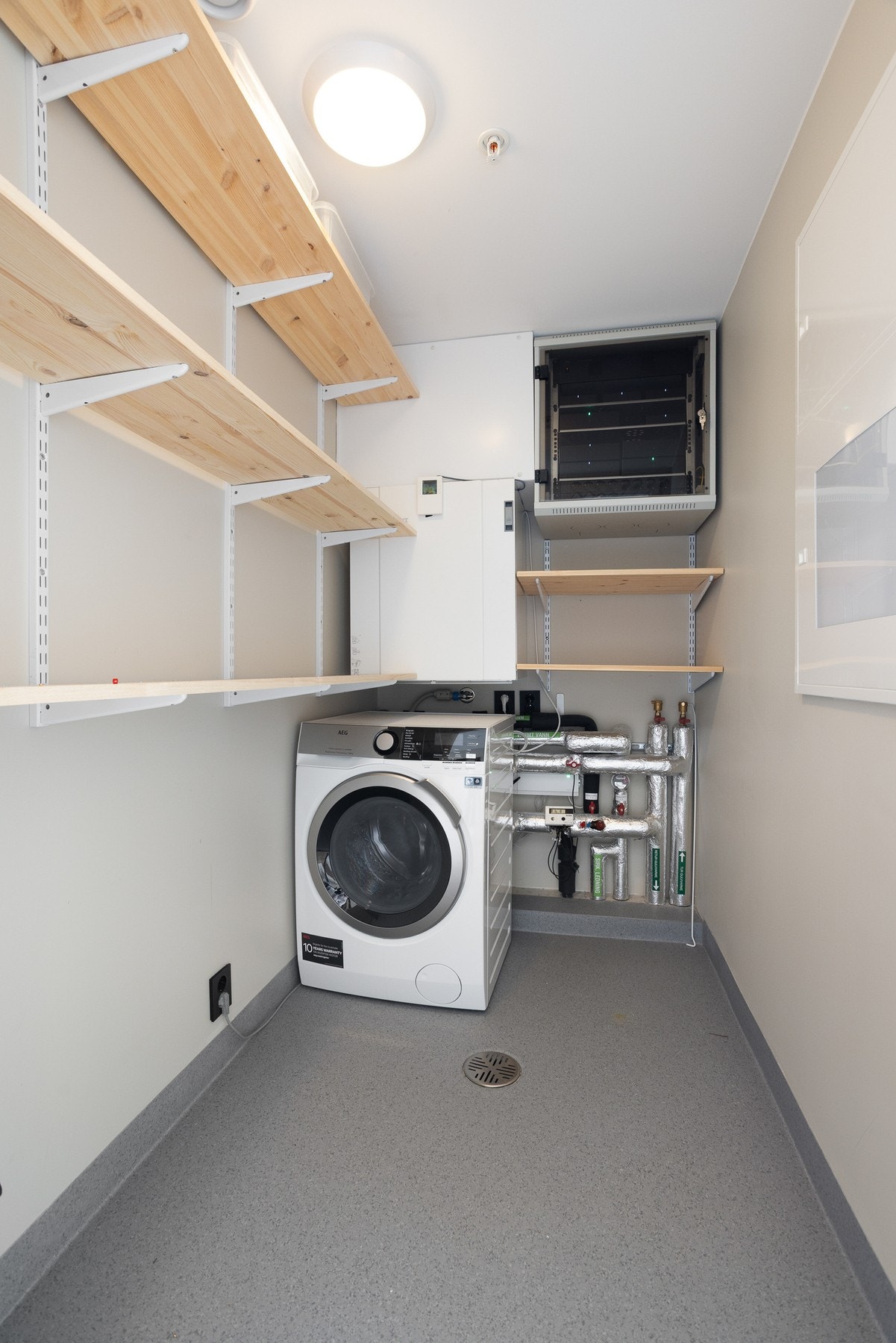 Bod/teknisk rom med opplegg for vaskemaskin og hylleløsninger. Galleribilde