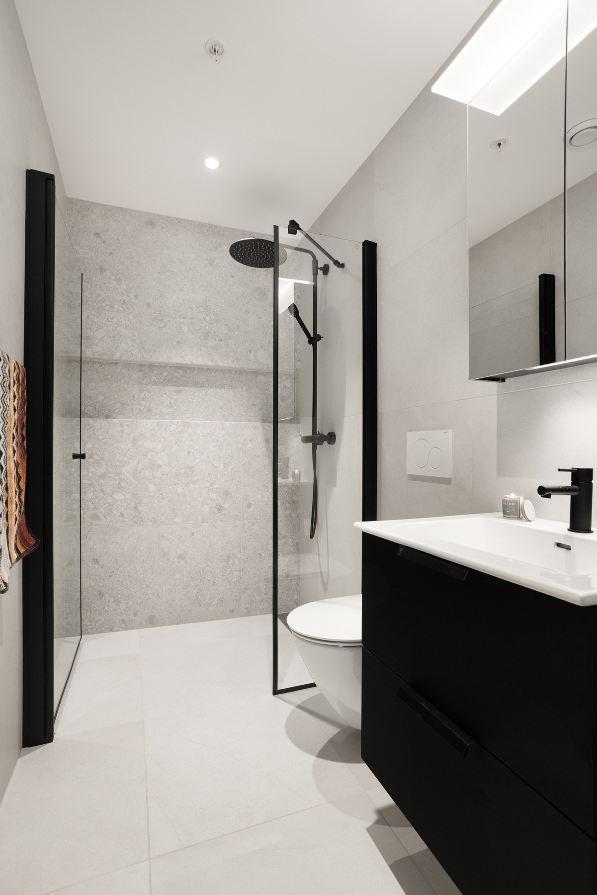 Det andre badet er også flislagt med servant i baderomsinnredning, veggmontert toalett og dusjnisje. Galleribilde