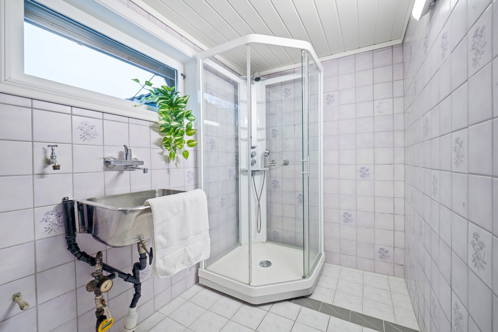 Enkelt bad med vegghengt utslagsvask, dusjkabinett og opplegg for vaskemaskin Galleribilde