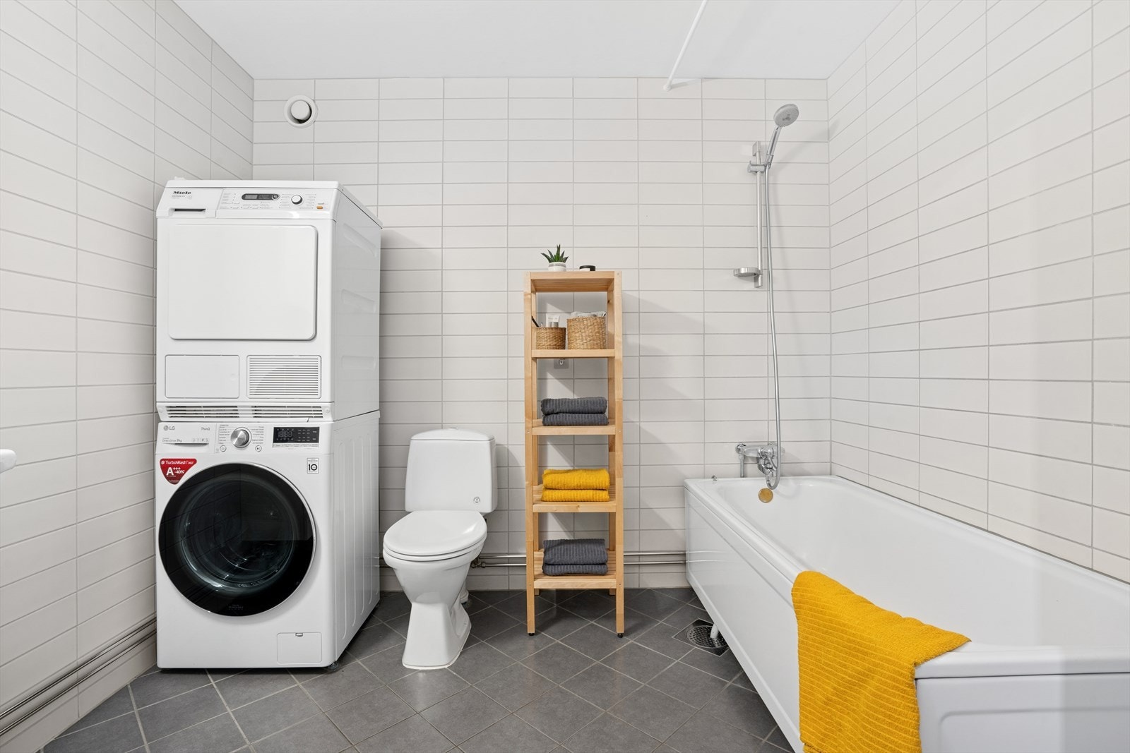 Flislagt bad med varmekabler i gulv. Her er det gulvstående wc og badekar. Opplegg for vaskemaskin og tørketrommel. Galleribilde