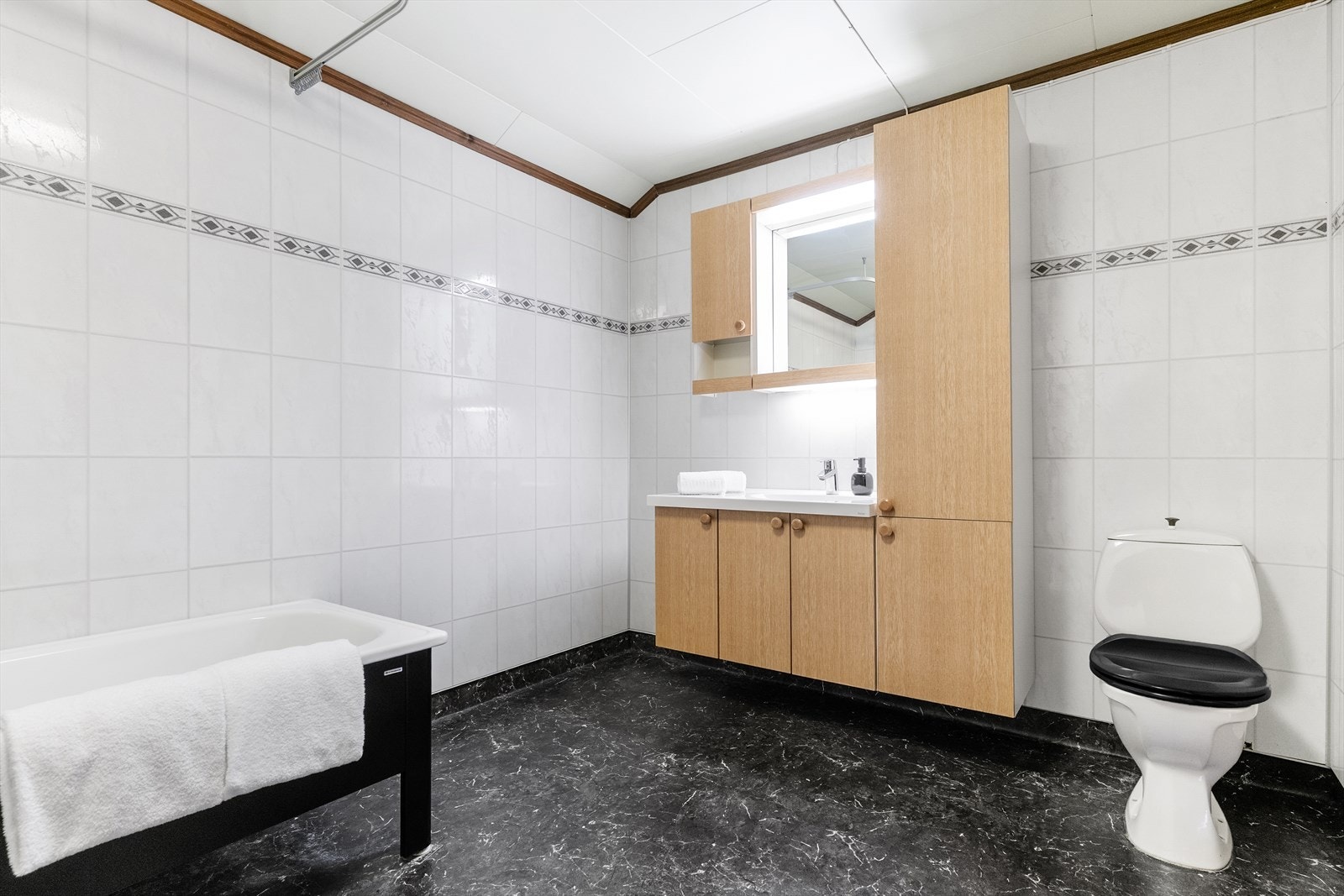 Badet er av ukjent aldrer. Badet inneholder klosett, vask med innredning, badekar med dusjgarnityr, skyllende med enkelt opplegg til vaskemaskin. Galleribilde