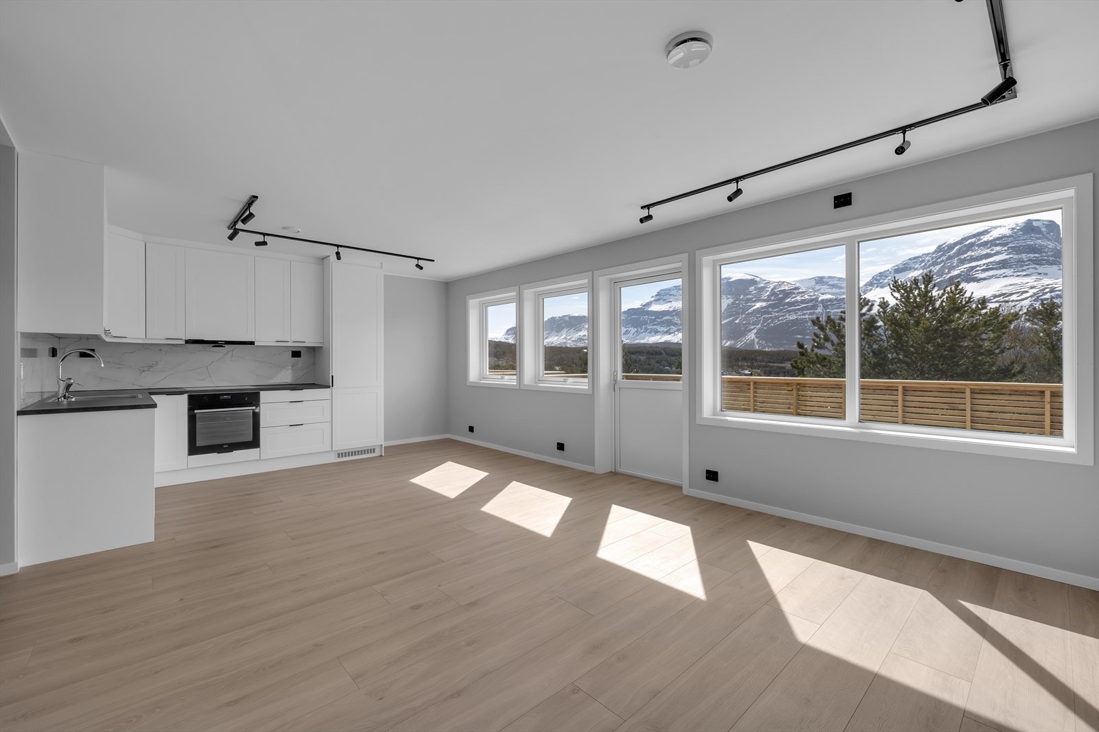 Åpen løsning mellom stue og kjøkken med flere møbleringsmuligheter Galleribilde