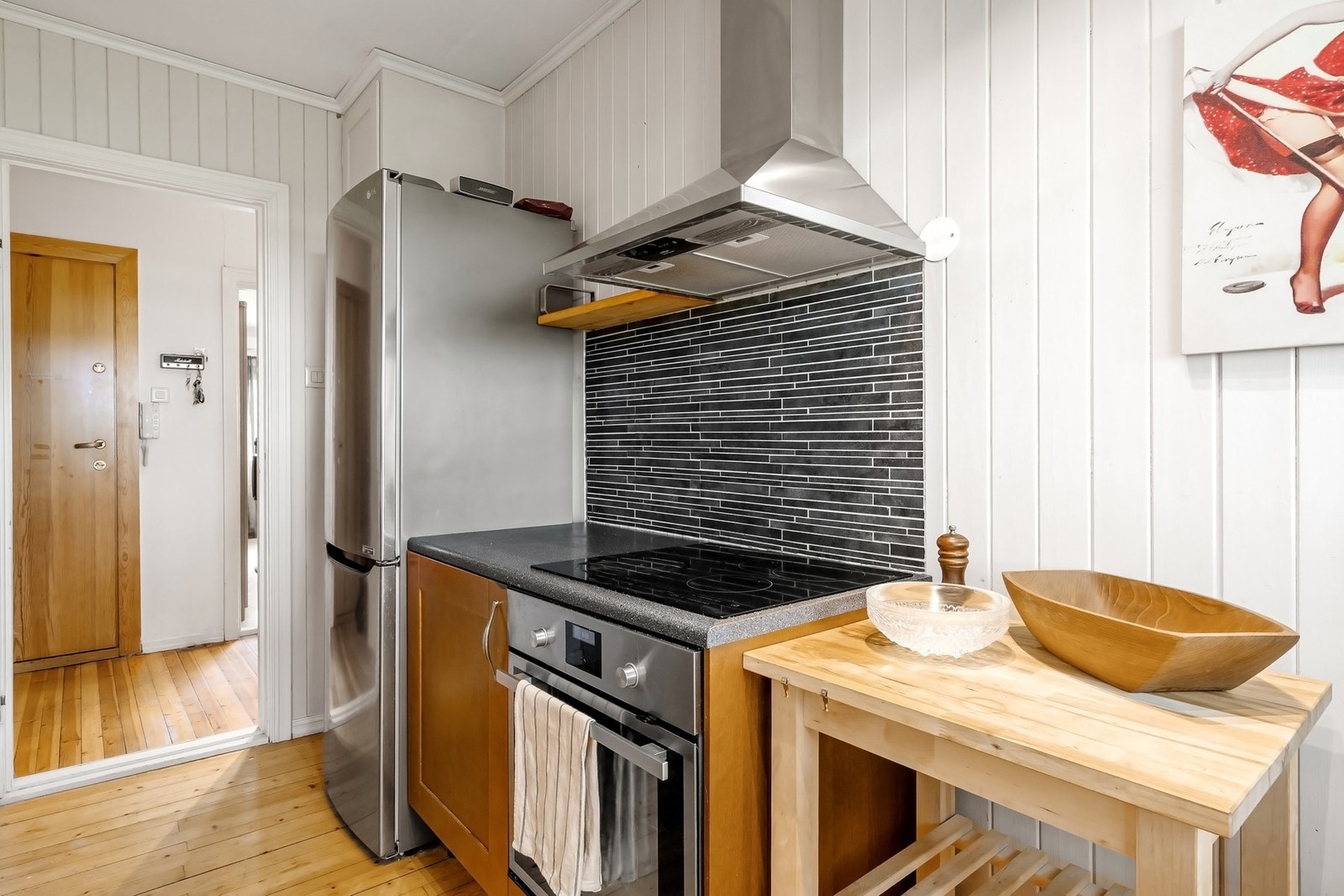 Kjøkkenet har hvitevarer som platetopp, stekeovn, oppvaskmaskin og kjøleskap med frysedel. Galleribilde