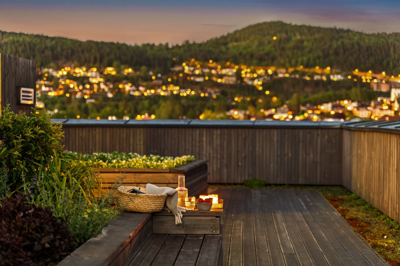 Felles takterrasse med utsikt over nærliggende boligområde og skogkledde åser i bakgrunnen. Galleribilde