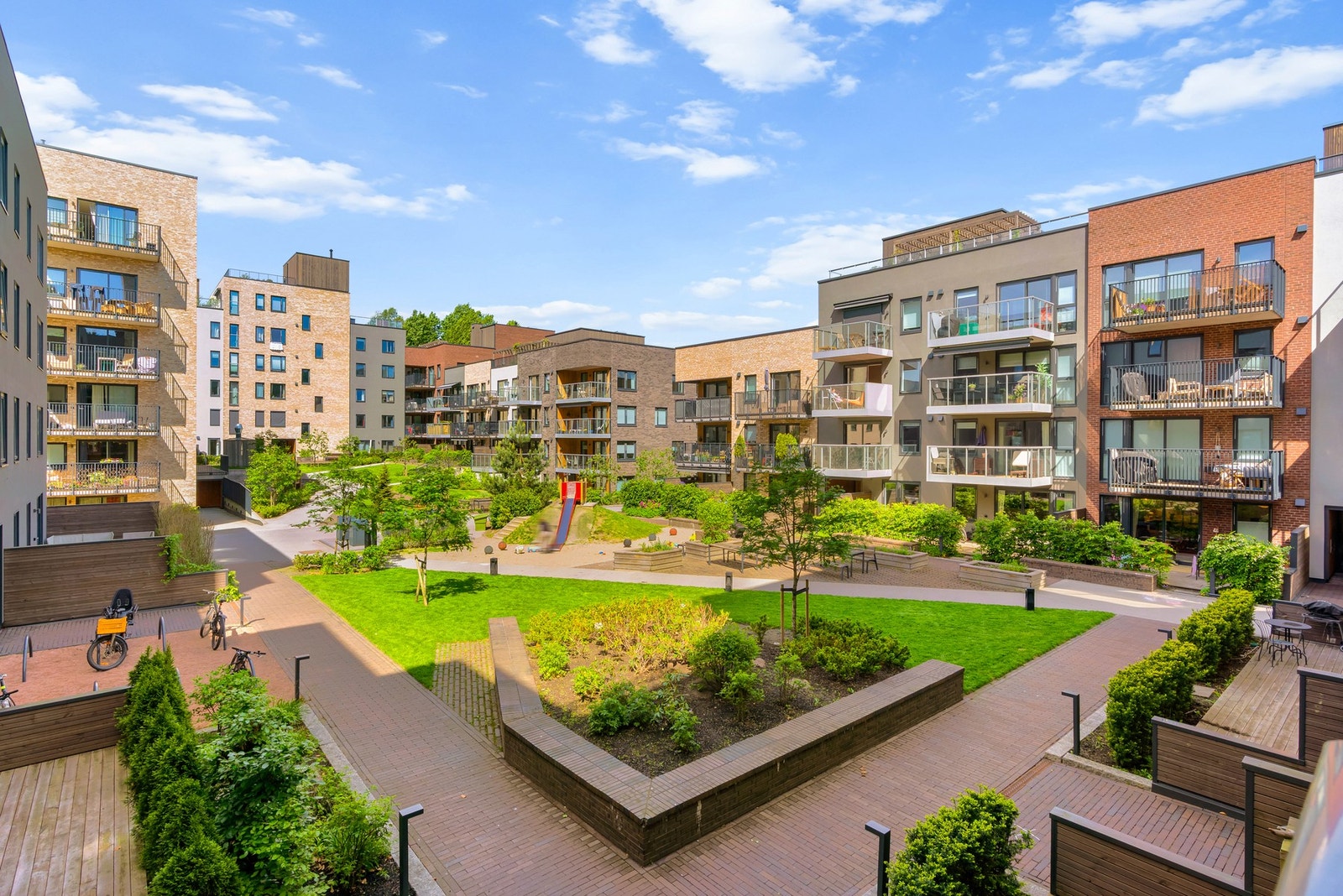 Tomten er pent og parkmessig opparbeidet med internveier belagt med betong og brostein, gressplener, busker, trær og bed samt lekeapparater og sittegrupper. Galleribilde