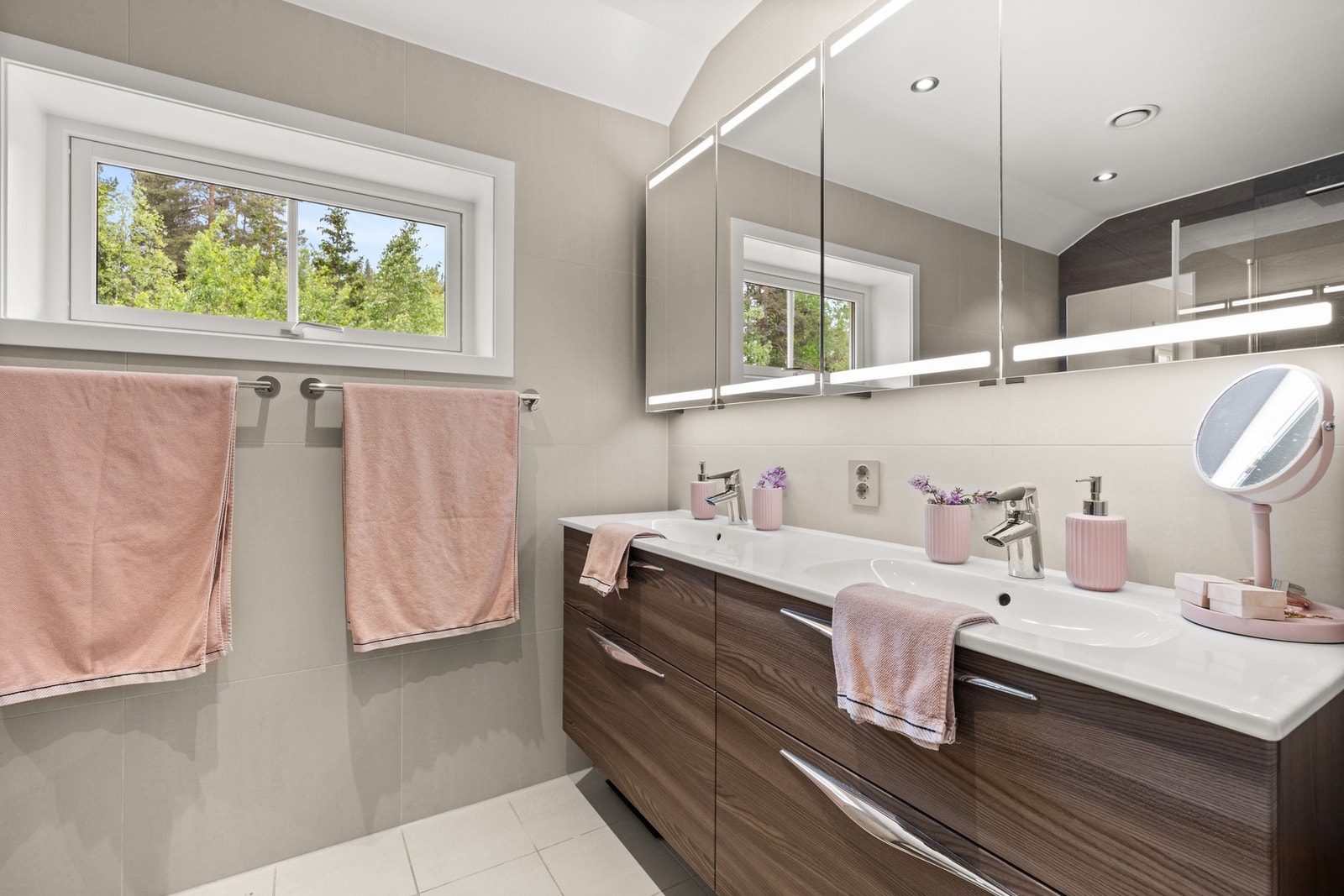 Flislagt bad fra 2018 med gulvvarme, dusjhjørne med glassdører, dobbel servant, vegghengt toalett og speil med belysning Galleribilde