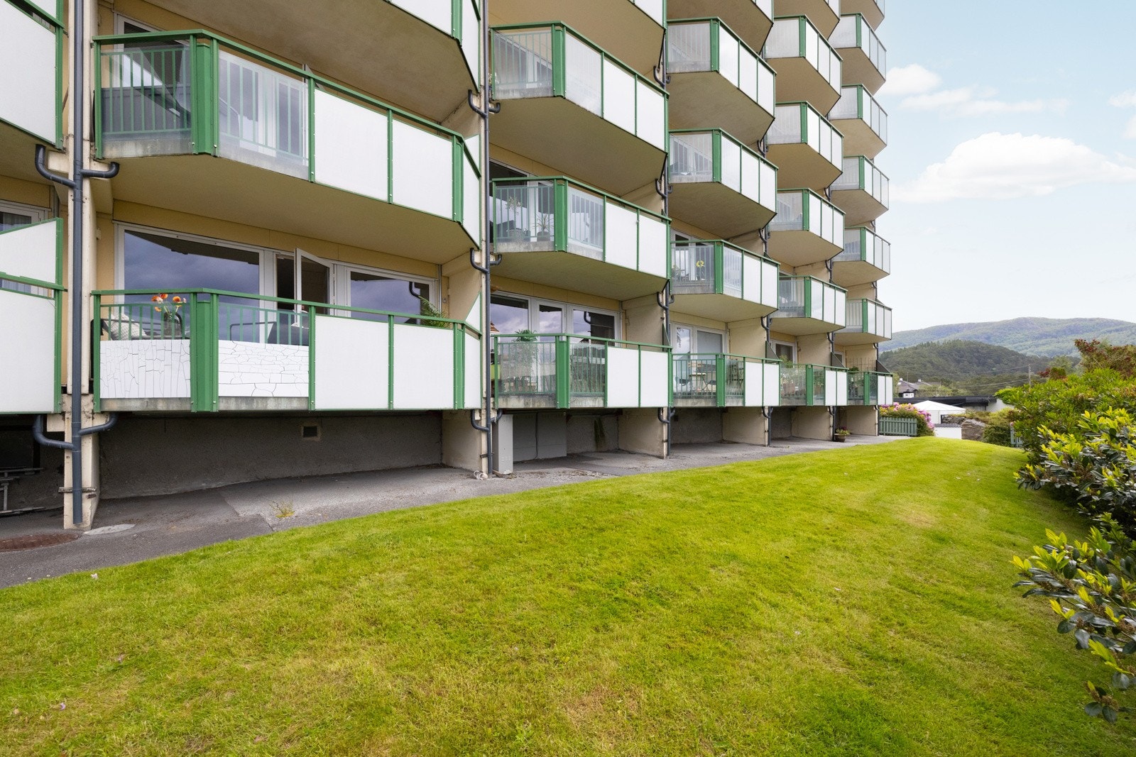 Aktuell leilighet ligger i en høy 1.etasje med plen og fin beplantning foran. Galleribilde