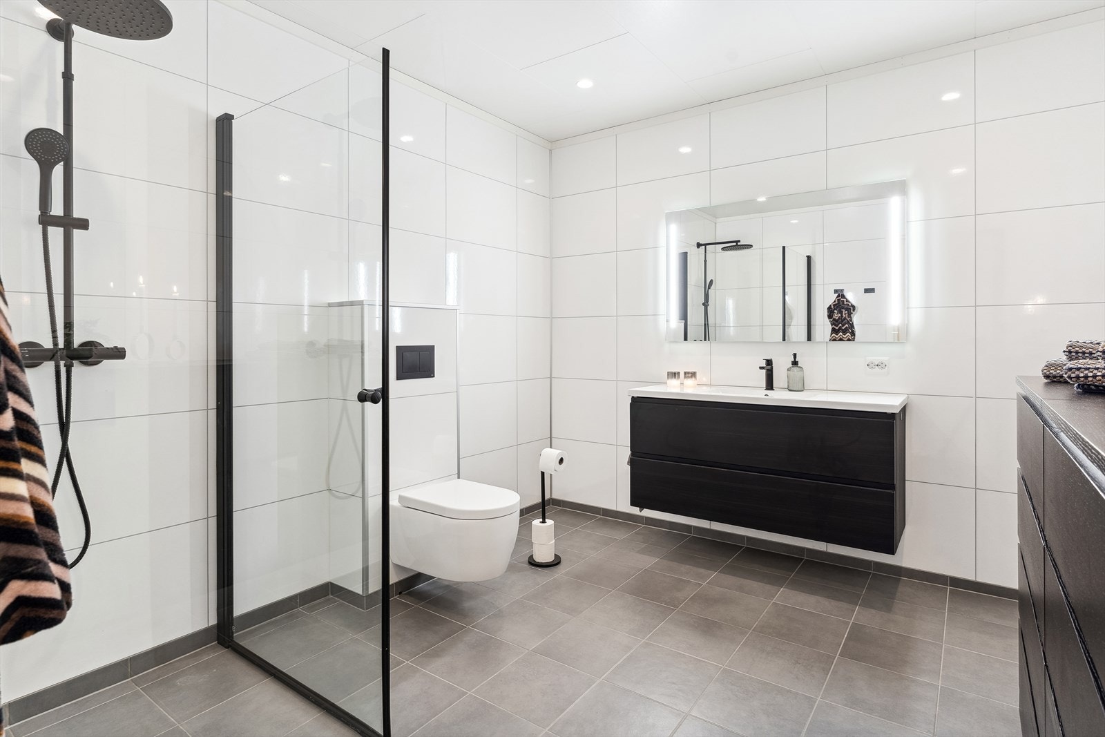 Badet er romsleg med flislagt golv, varmekablar og downlights i himling. Galleribilde