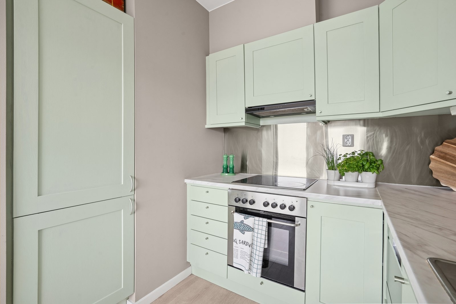 Malte fronter, laminat benkeplate med rusfritt nedfelt oppvaskbeslag, ett greps batteri, lys og plate mellom over- og underskap. Galleribilde