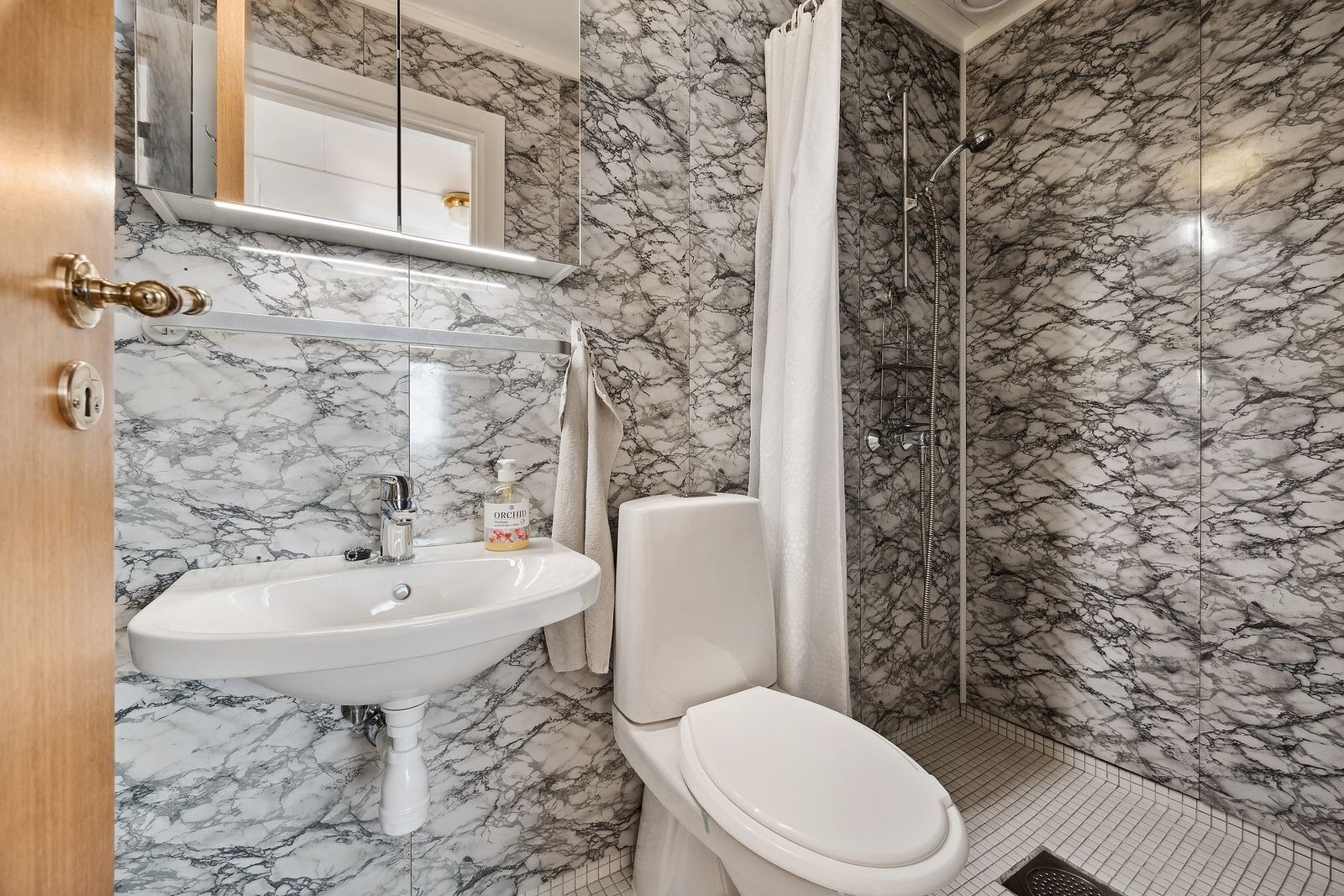 Bad med varmekabler i gulv og vifte med avtrykk over tak med motor på loftet som går kontinuerlig. Galleribilde