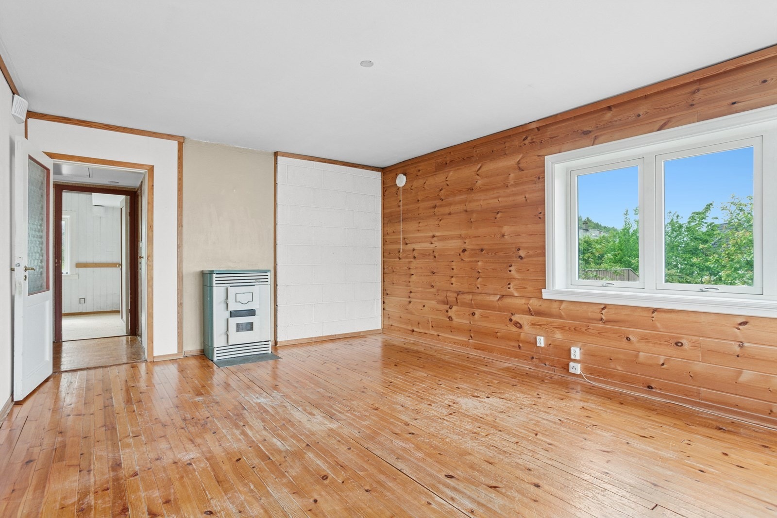 Kamin for fast brensel i stue. Lakket tregulv og panel på vegger. Balansert ventilasjon med varmegjennvinning. Galleribilde
