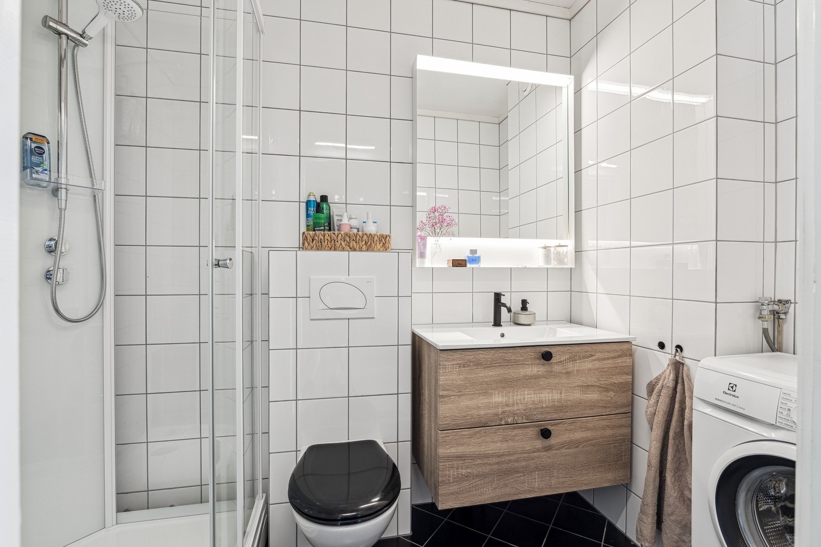 Flislagt bad med dusjkabinett, vegghengt toalett, servant m/innredning og vaskemaskin Galleribilde