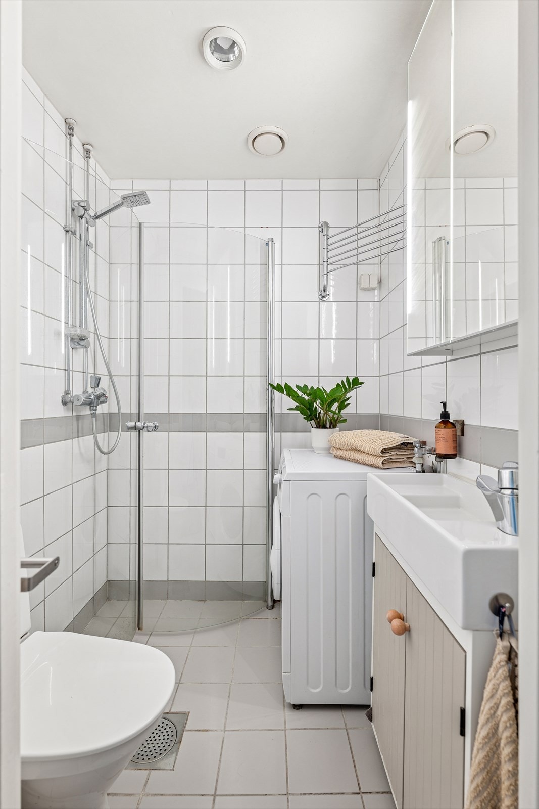 Baderommet er både moderne og funksjonelt, og inneholder et stilrent dusjhjørne, toalett, servant med underskap og opplegg til vaskemaskin. Vaskemaskin medfølger boligen. Galleribilde