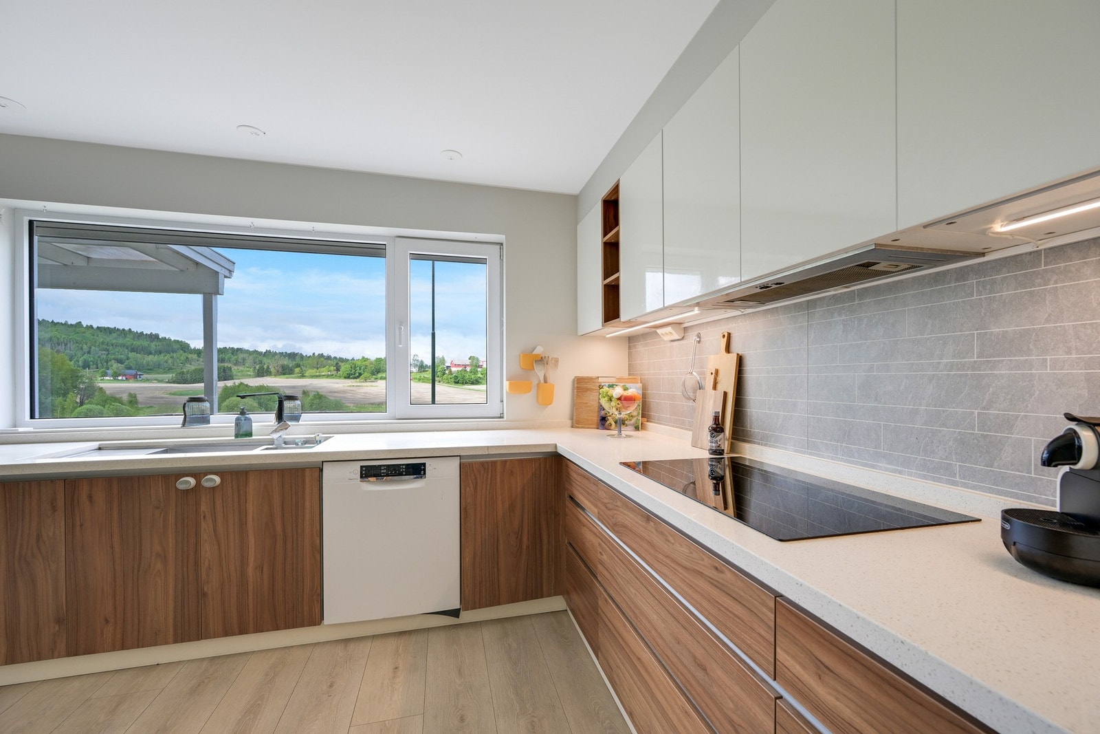 Leiligheten har et stilrent kjøkken med integrerte hvitevarer. Det er pene overflater og godt med skap, skuff- og benkeplass. Galleribilde