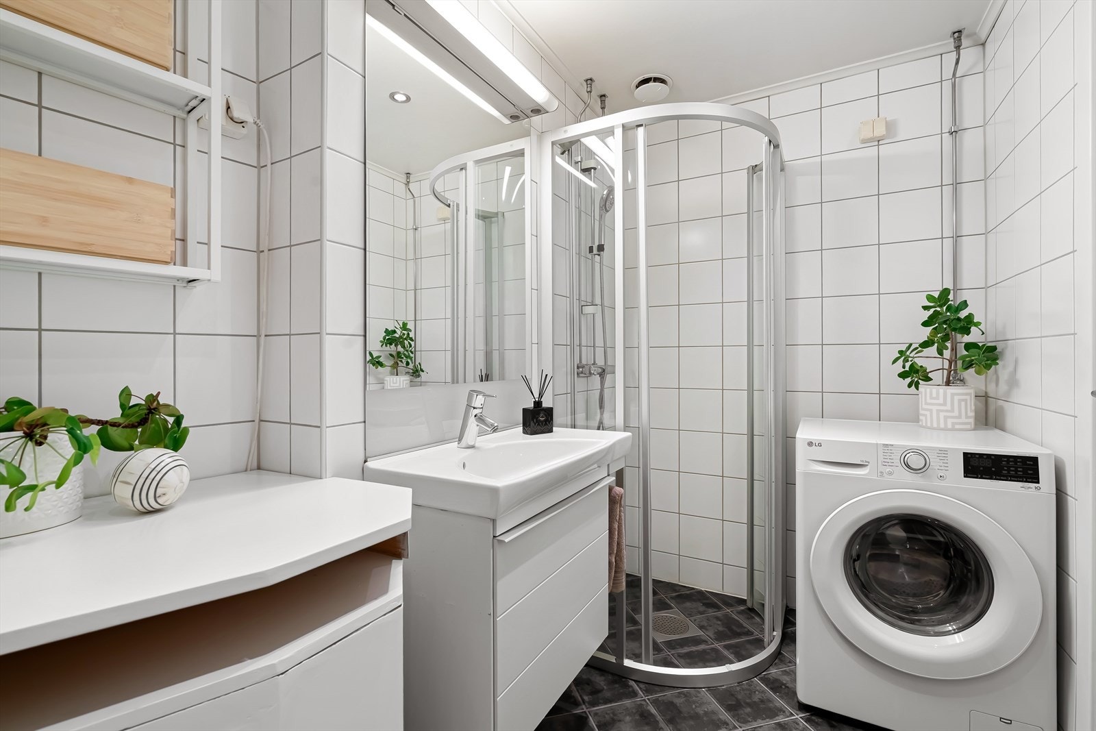 Badet har dusj med skyvedører i herdet glass og klosett og opplegg for vaskemaskin Galleribilde