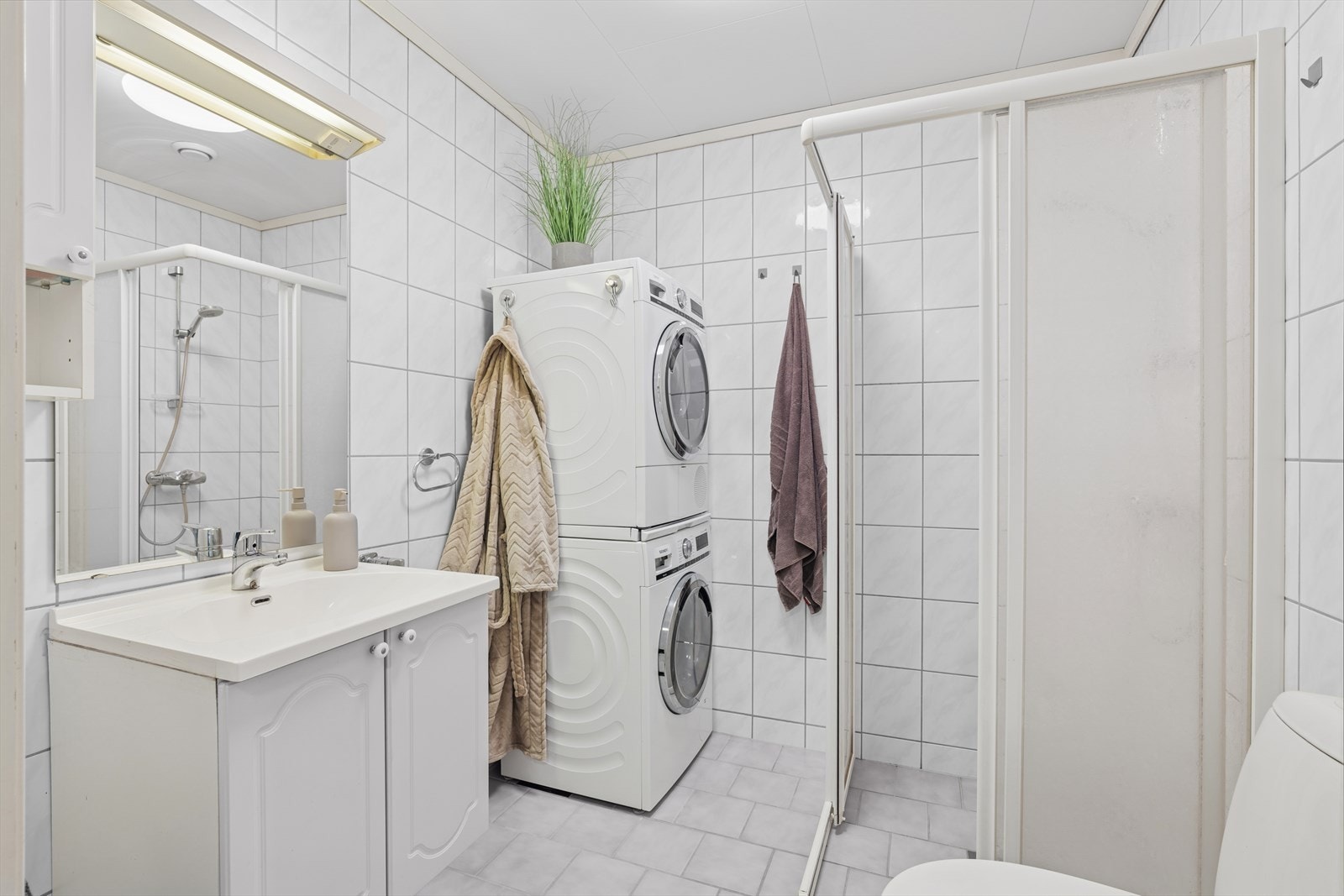Badet ligger praktisk plassert rett ved entréen og har en funksjonell innredning med dusjhjørne og vaskemaskinopplegg Galleribilde