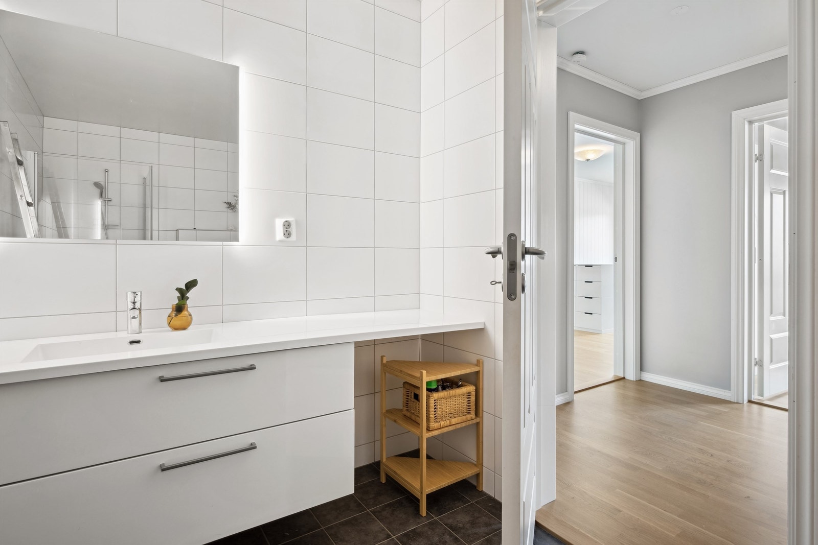 Badet er innredet med servant i hel benkeplate med dobbel skuffeinnredning under deler av benkeplaten. Vegghengt speil med integrert lys bak, dusjhjørne med innfellbare vegger og veggmontert toalett. Det er balansert ventilasjon i rommet. Galleribilde