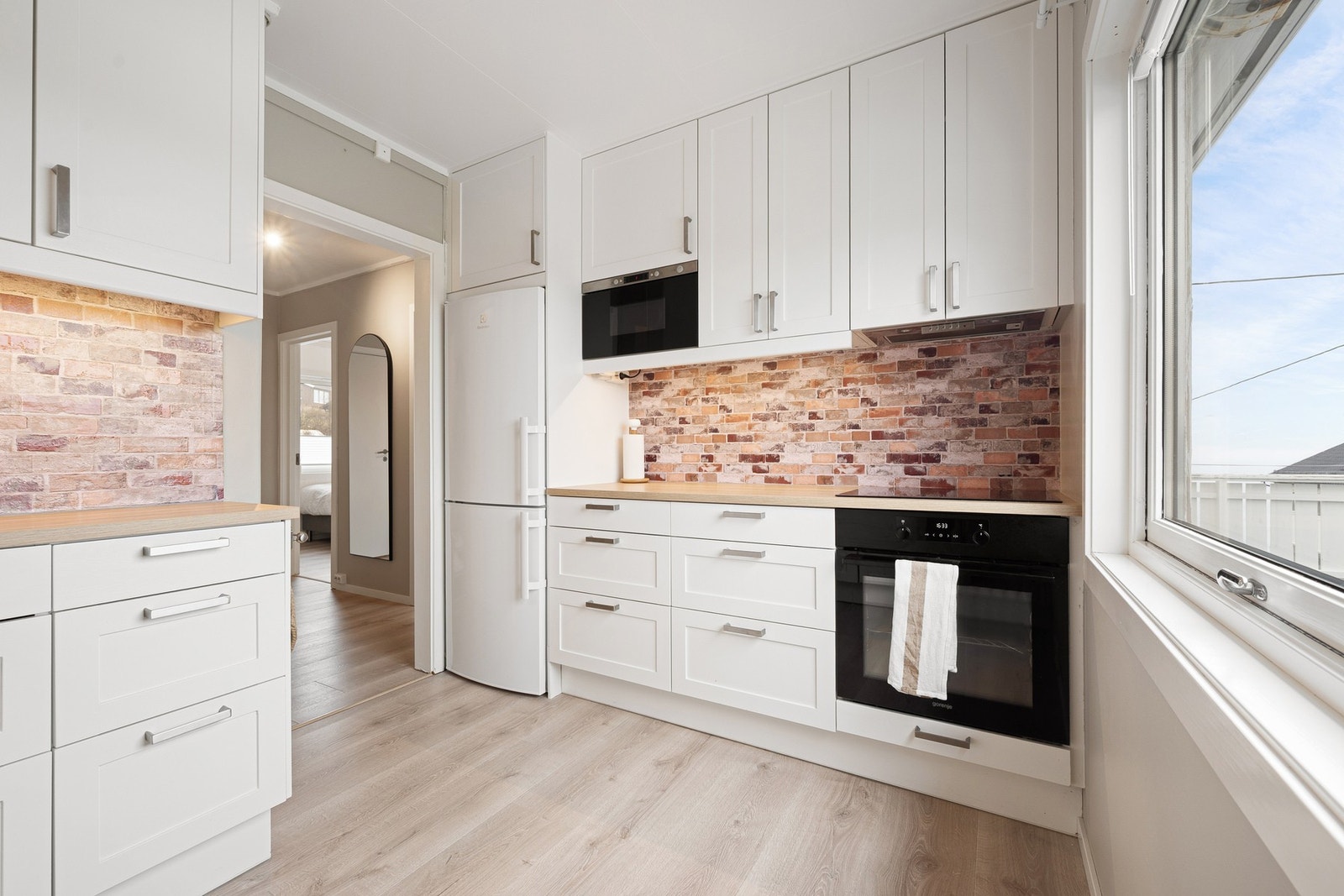 Kjøkkeninnredning med lyse profilerte fronter og takhøye overskap Galleribilde