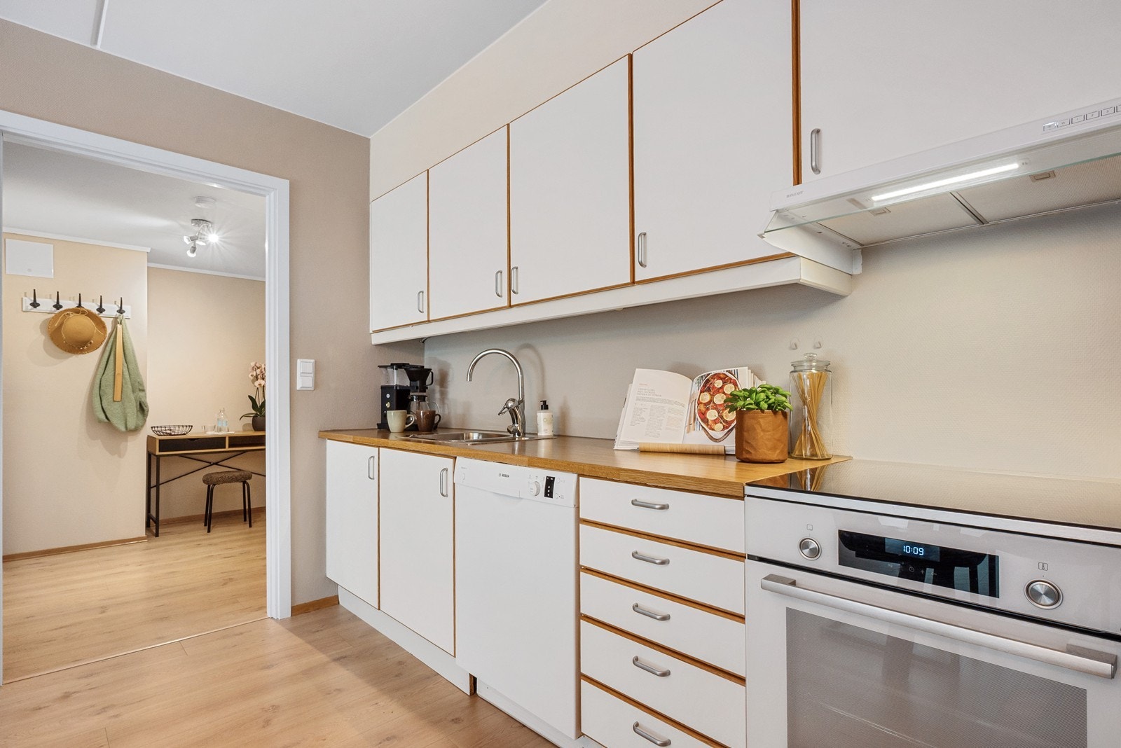 Innredningen har hvite, glatte fronter og trehvit ramme, kombinert med benkeplate i trehvit laminat. Galleribilde