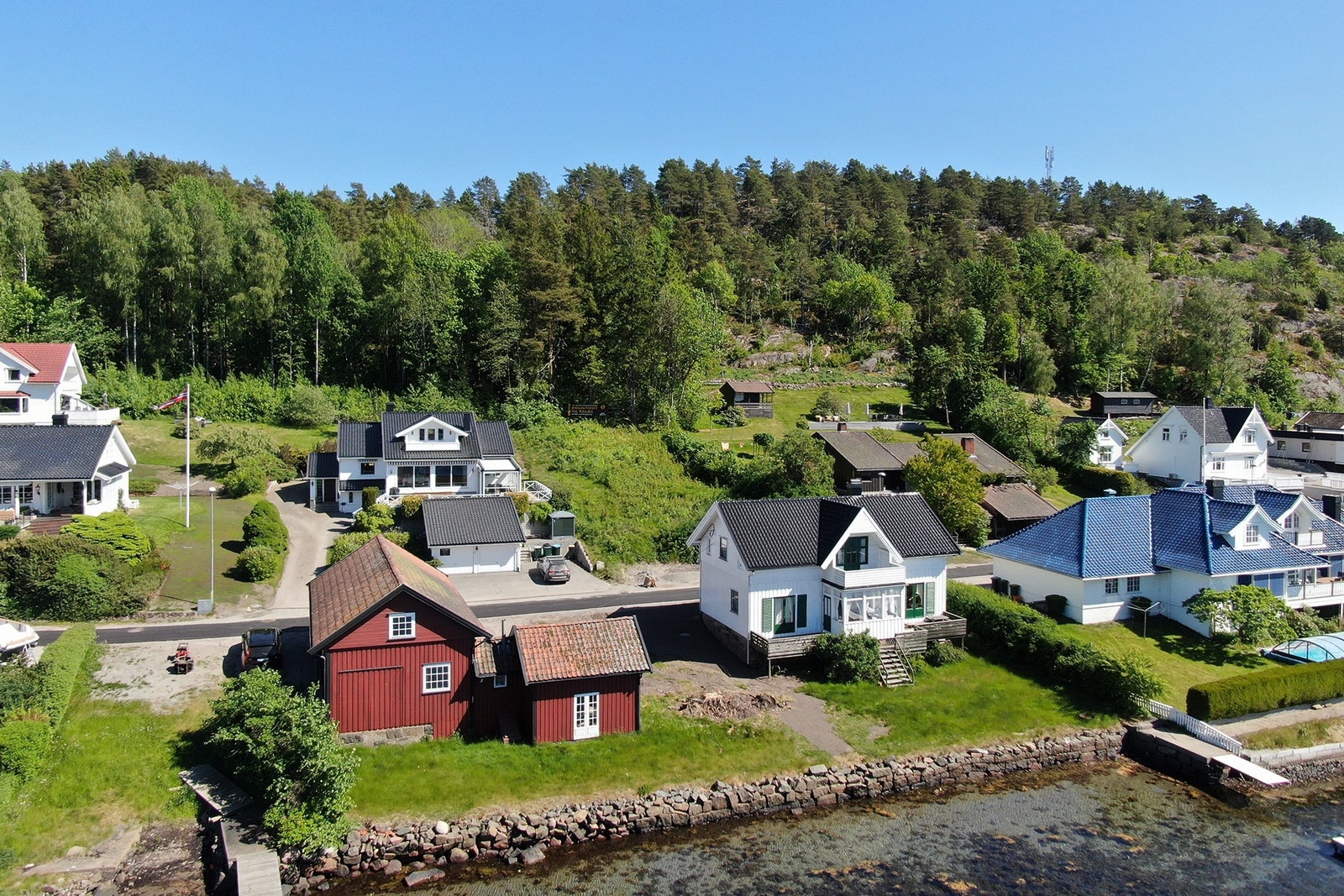 Tomten sett fra sjøen. Ligger rett i bakkant av det hvite huset med sort tak Galleribilde