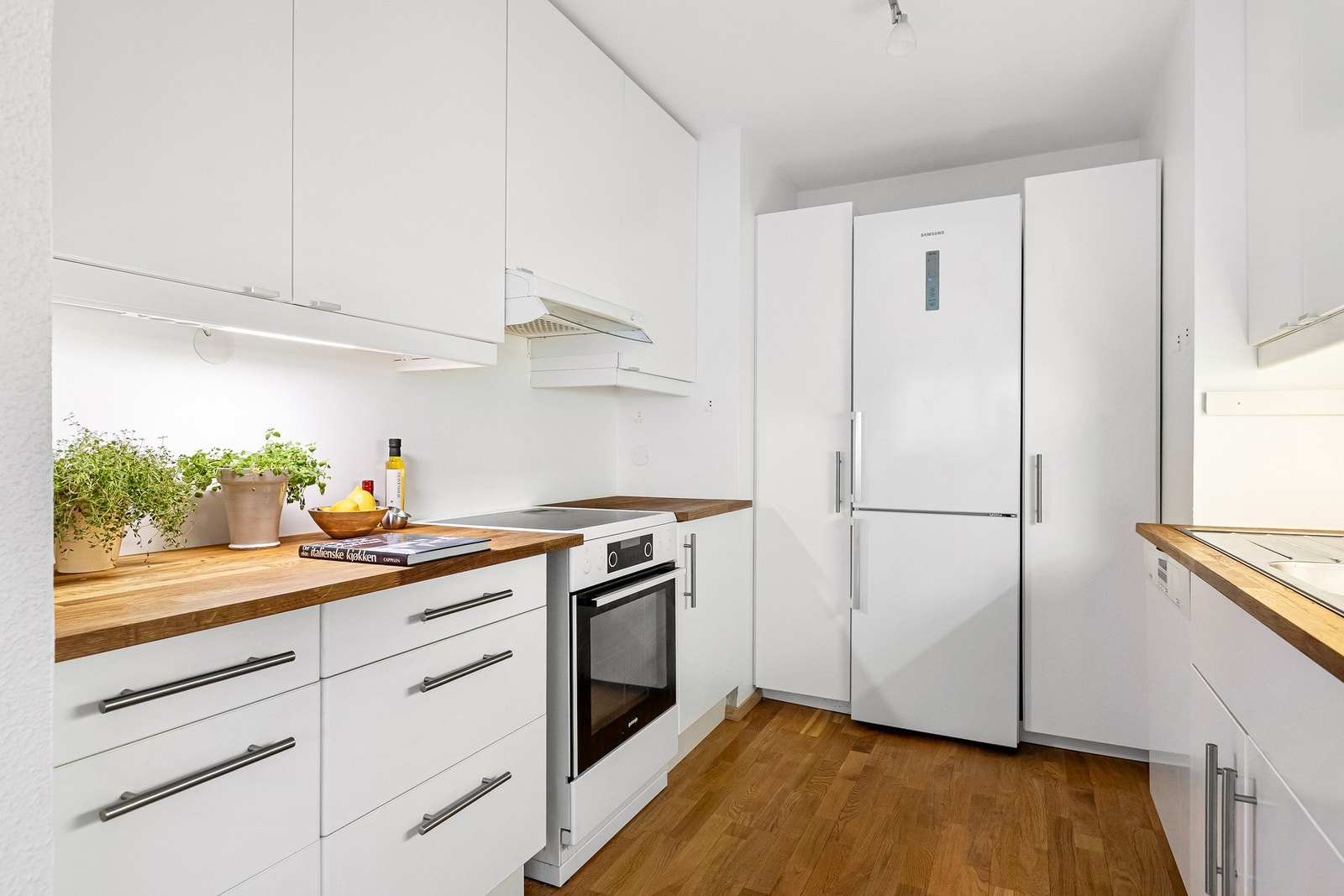 Kjøkkenet har en stilren IKEA-innredning fra 2012 med slette, lakkerte fronter og benkeplate i heltre eik. Galleribilde