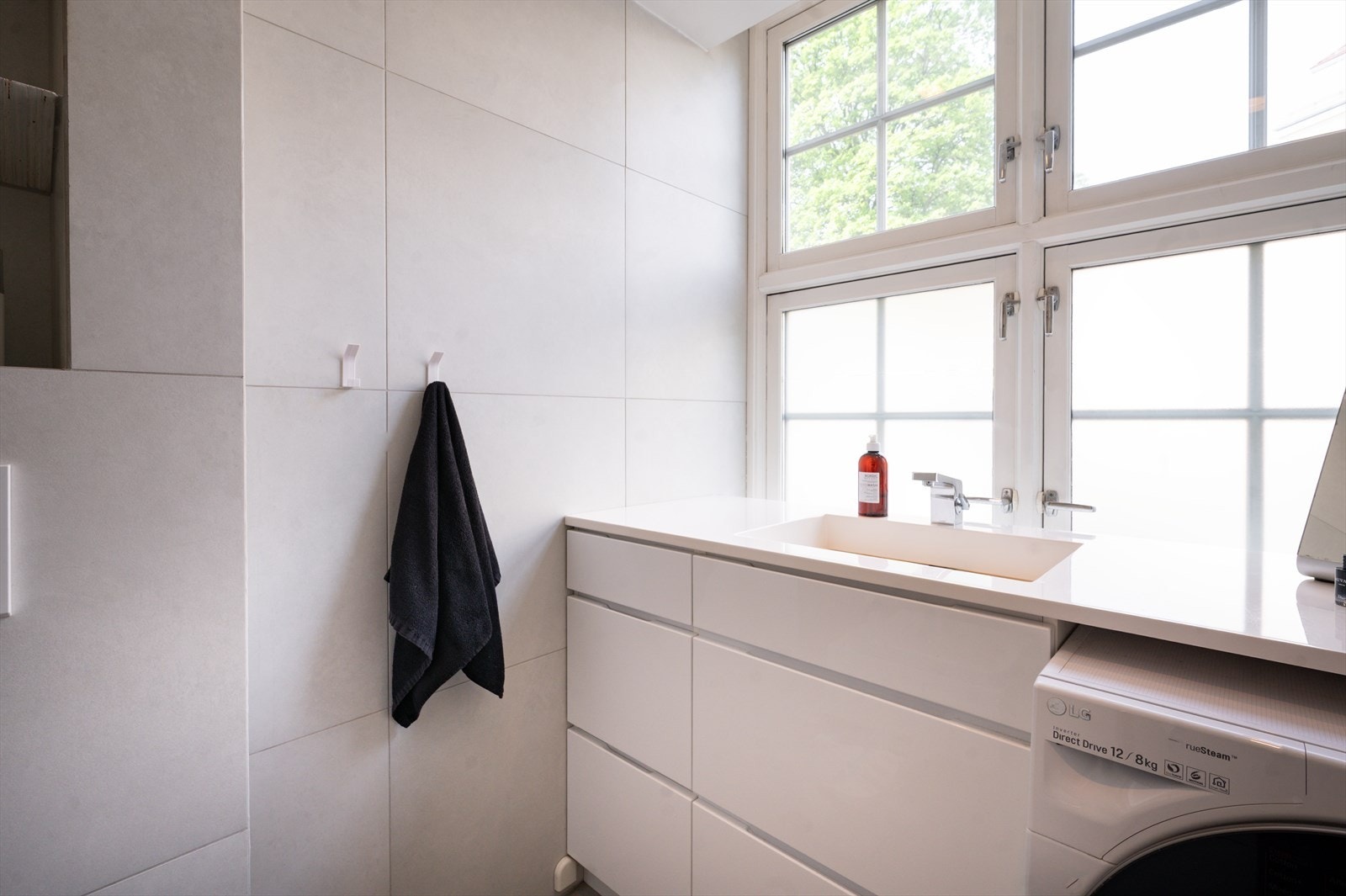 Innredet med vegghengt toalett, servant nedfelt i benkeplate og dusjhjørne med svingbare glassdører. Galleribilde