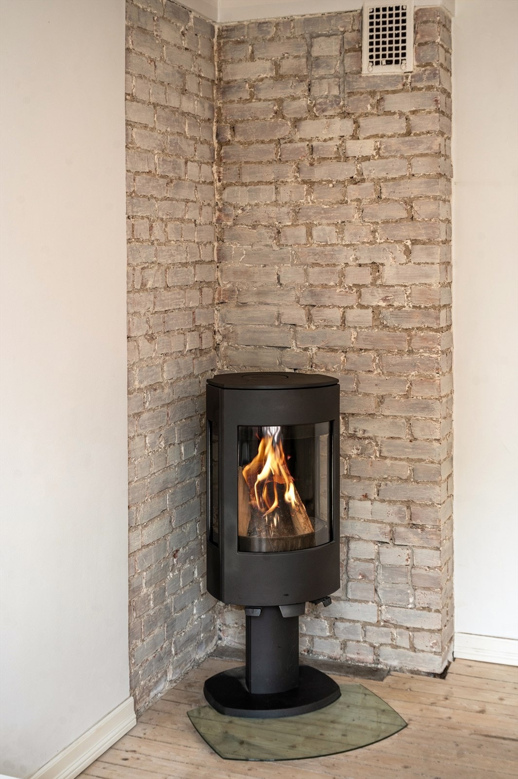 Teglsteinsvegg bak peisen gir rommet særpreg og lunhet. Galleribilde