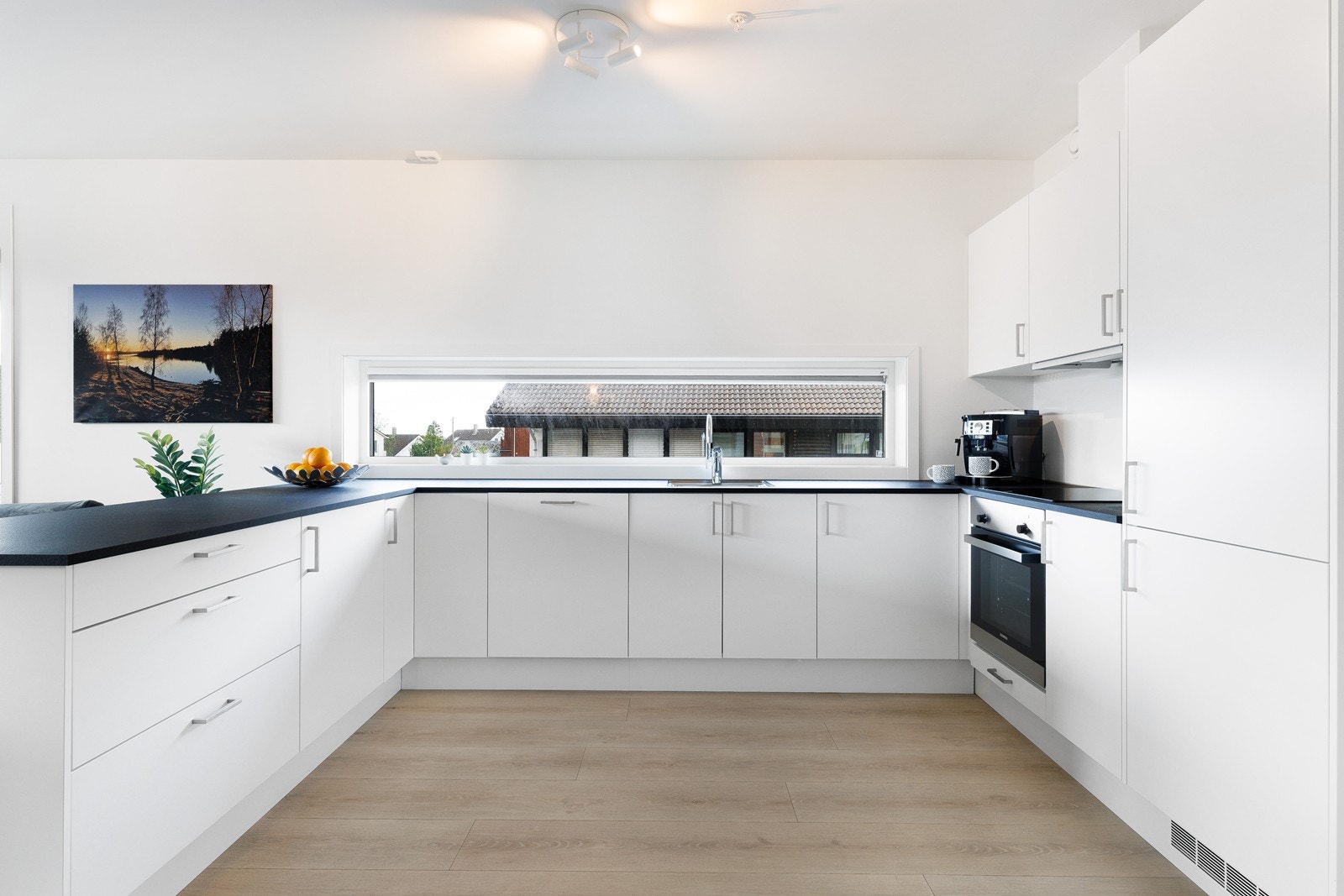 Kjøkkenet er innredet med koketopp, stekeovn, oppvaskmaskin og kjøleskap. Galleribilde