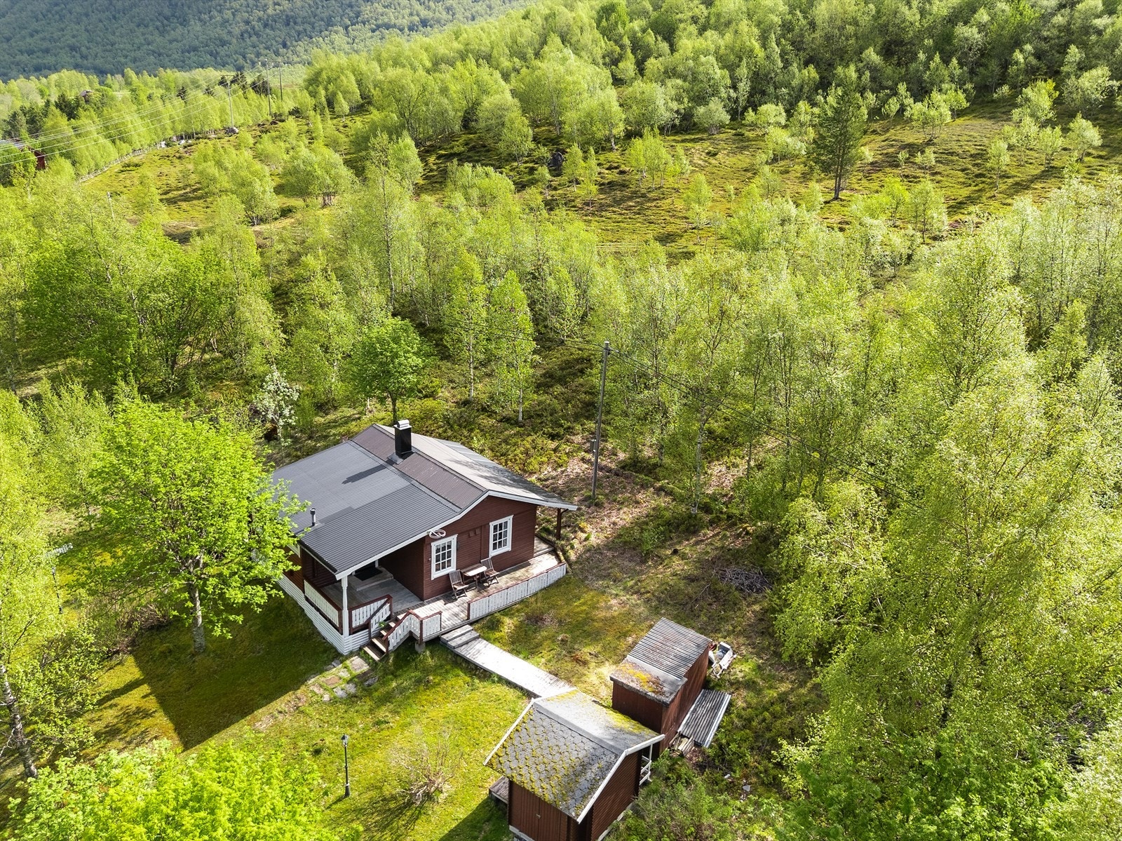 Eiendommen består av en hytte med stor terrasse som omkranser 3 sider av boligen, samt utedo og flere uteboder. Galleribilde