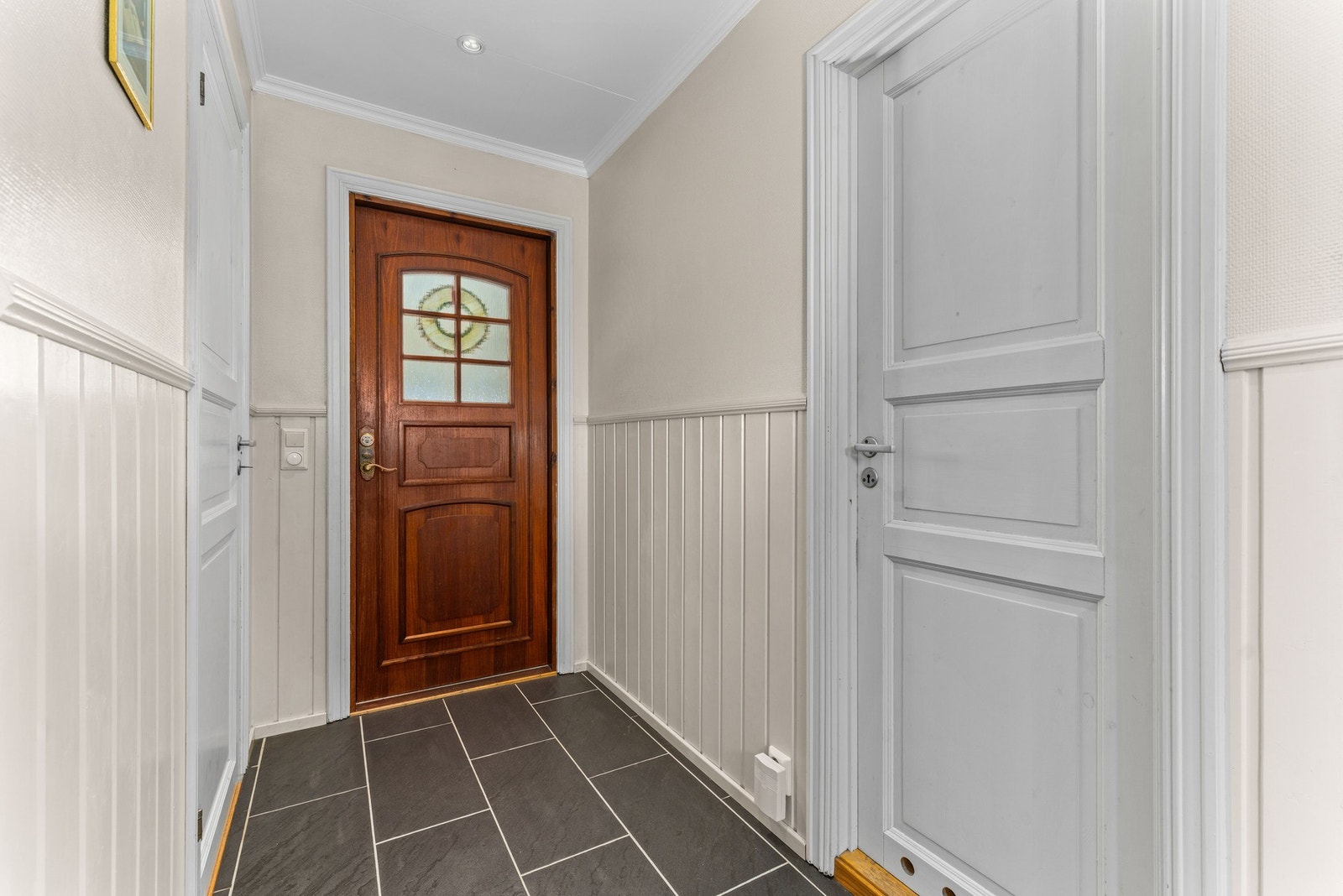 Boligen ønsker deg velkommen med en lys og romslig entré, med flislagt gulv og trepanel på veggene. Galleribilde