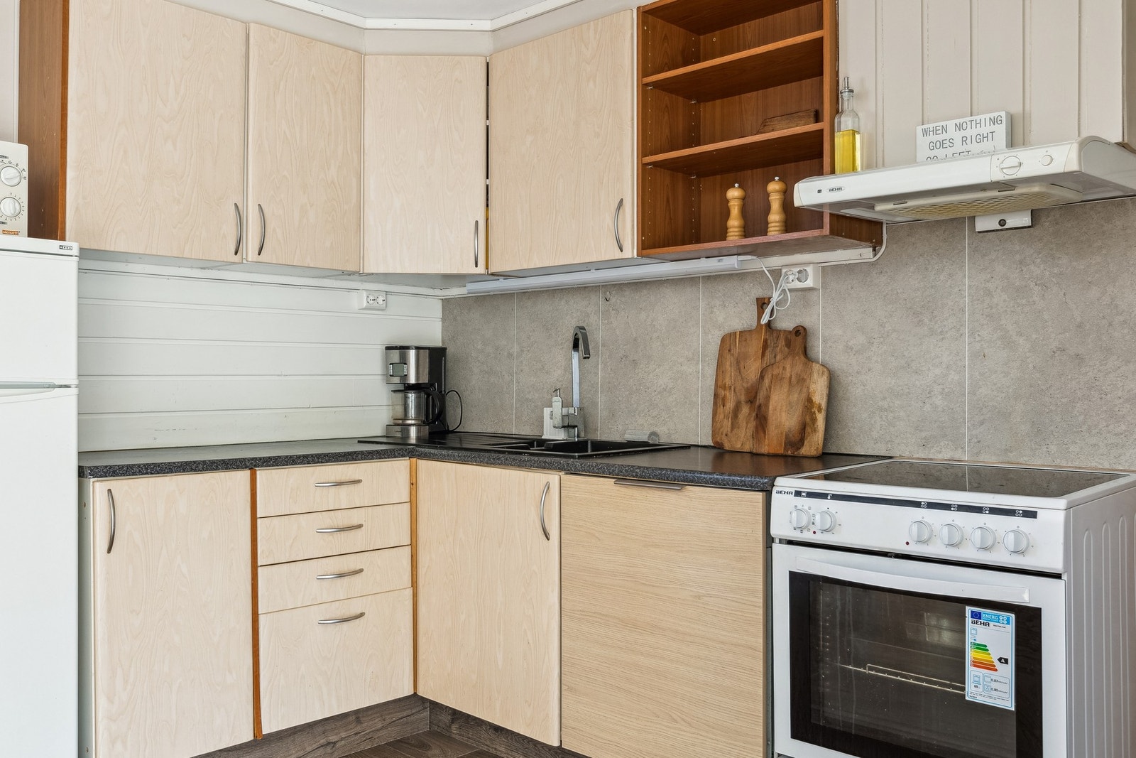 Kjøkkeninnredning med malte glatte fronter. Laminat benkeplate med nedfelt benkebeslag med 2 kummer. Avtrekkshette over stekesone. Galleribilde